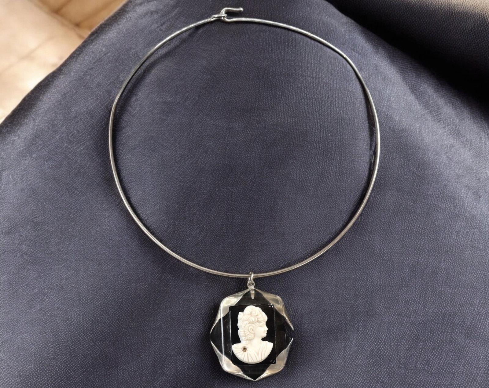 EUROPE: Vintage Silver-Tone Choker Necklace - Cameo Pendant, 16x12cm: A striking vintage choker necklace, featuring a sleek silver-tone rigid band with a gracefully suspended octagonal faceted glass pendant. The pendant showcases an elegant white cameo of a classical la