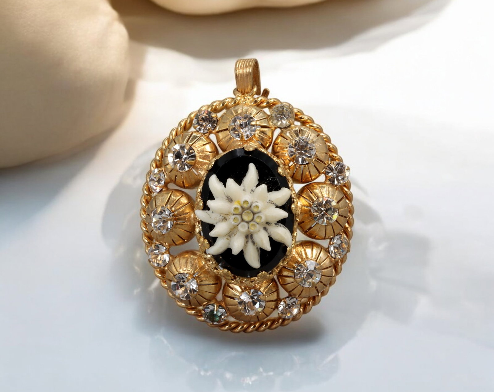 AUSTRIAN FOLK REVIVAL: Pendant - Edelweiss Motif with Rhinestones, 4 x 3 cm: Radiating Alpine charm, this Austrian Folk Revival pendant features a central edelweiss bloom - symbol of purity and mountain heritage - set in high relief against a glossy black ground. Measuring 4 x