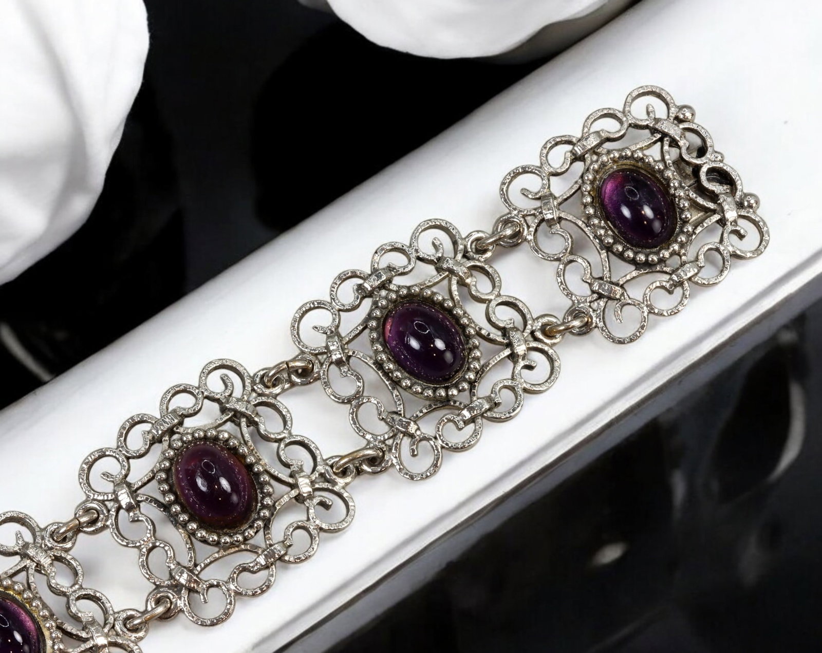 VINTAGE SILVER FILIGREE BRACELET WITH PURPLE CABOCHONS - 17.5cm, 56g: A striking vintage silver filigree bracelet, measuring 17.5 cm in length and weighing 56g. This elegantly crafted bracelet showcases a series of ornate filigree links, each adorned with a deep purple 