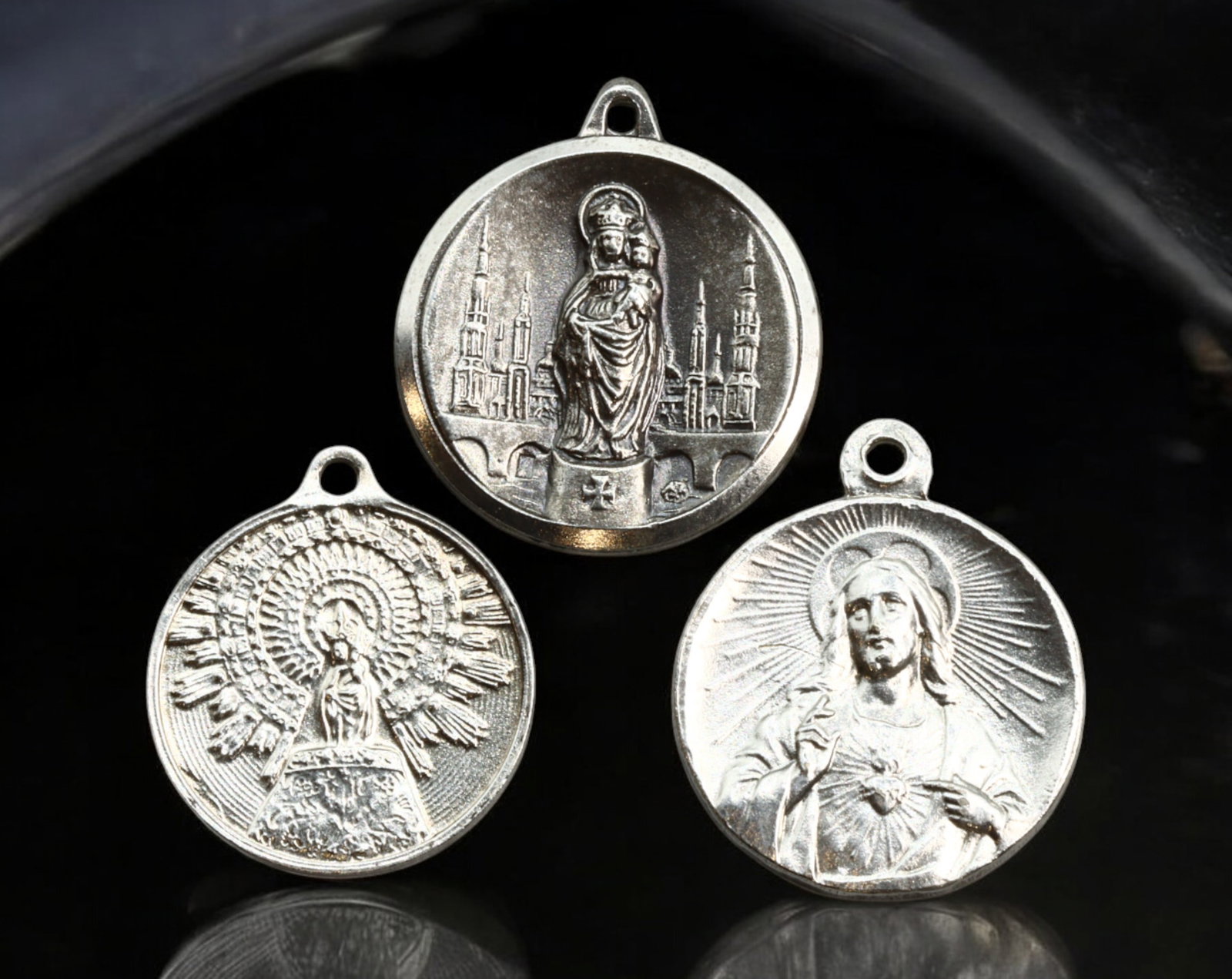 SPAIN: Religious Devotional Medals - Silver, Sacred Heart & Marian Devotions, 20th Century: A set of three silver devotional medals, each measuring approximately 2-2.3 cm in diameter with a combined weight of 10g. The designs feature a radiant depiction of the Sacred Heart of Jesus, an intri