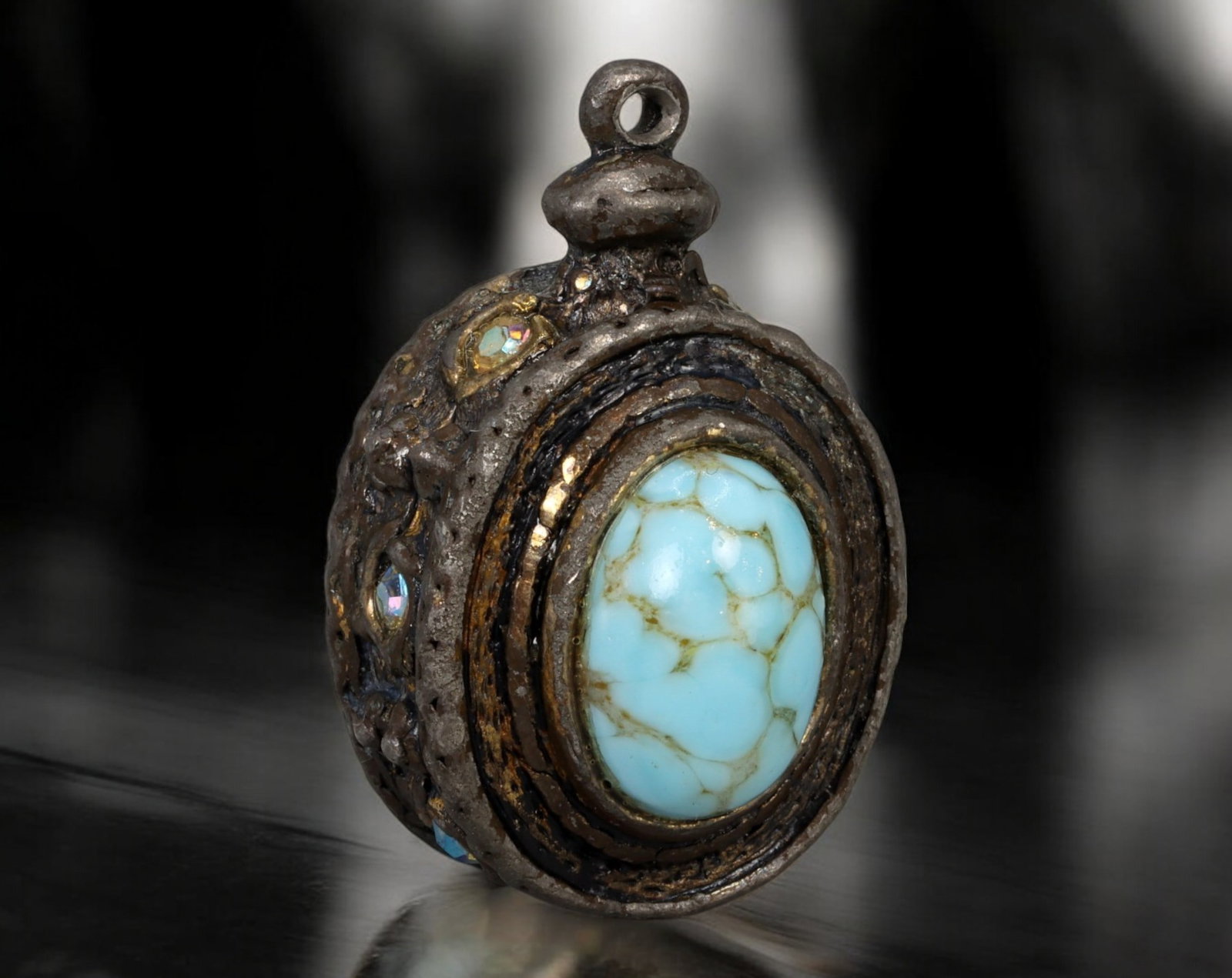 CENTRAL ASIA: Tribal Amulet Pendant - Bronze Alloy, Turquoise & Glass Insets, 19th Century: A bold and enigmatic tribal amulet pendant from Central Asia, measuring 2.5 x 1.7 cm and weighing 15g, likely fashioned in a bronze-based alloy with a rich, time-darkened patina. The piece features pr