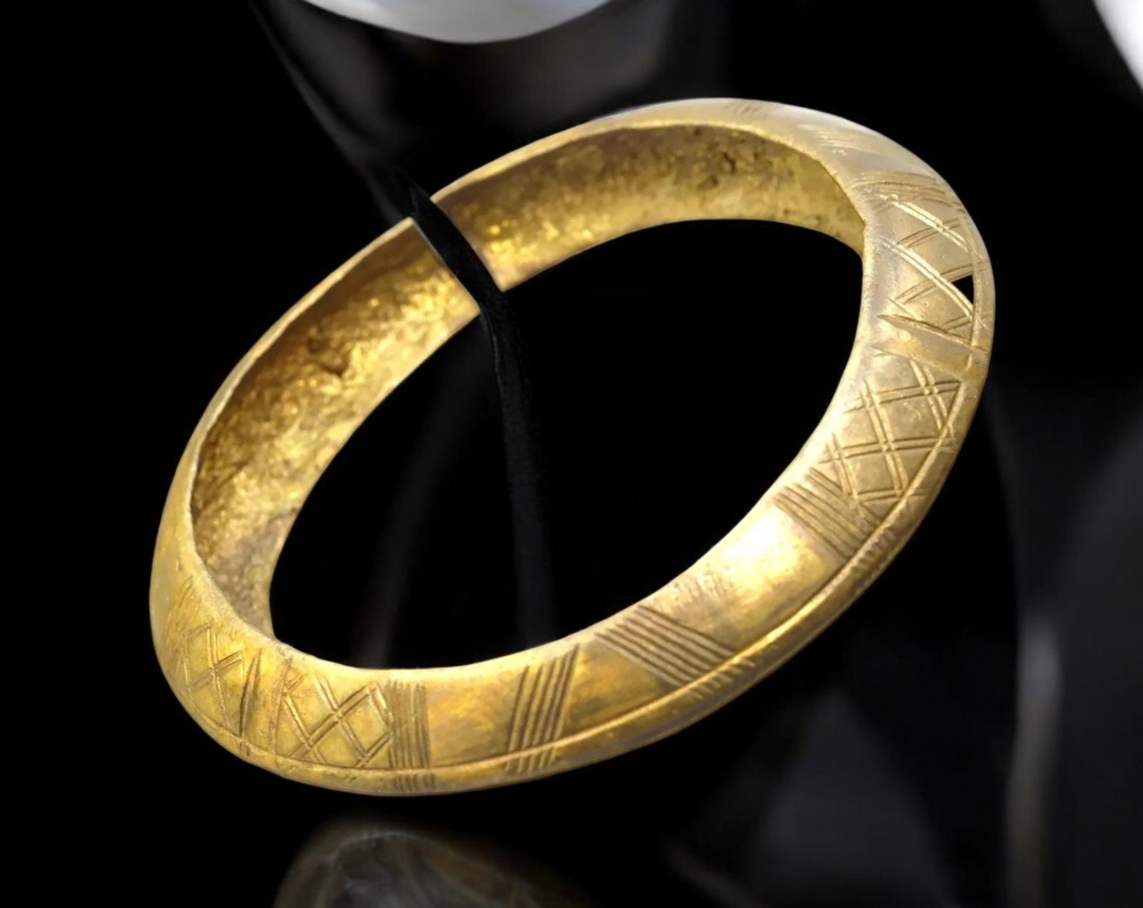 AFRICAN TRADE: Gilt Bangle - Incised Crosshatch Motif, West Africa, 8.8 cm Diameter: This refined West African gilt bangle exemplifies the interplay between weight, symbolism, and surface rhythm in traditional cast adornment. Measuring 8.8 cm in diameter and weighing 95 g, the bracele