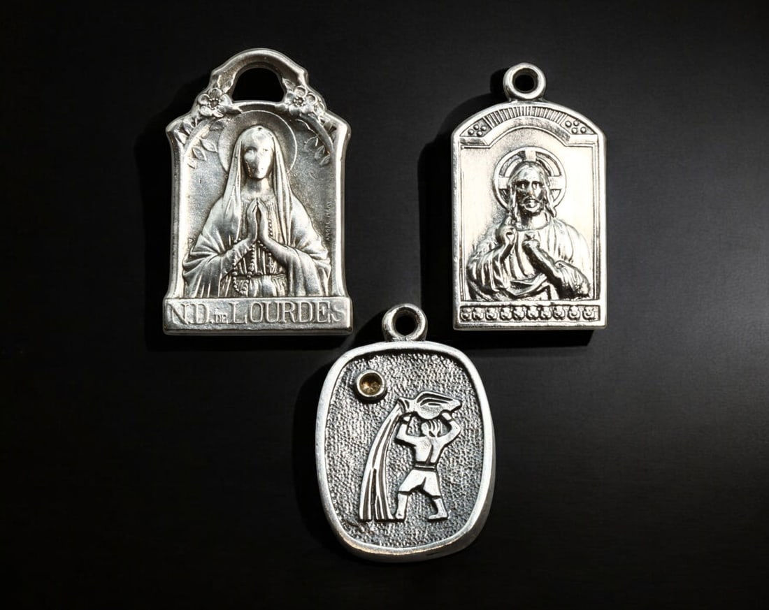 FRANCE: Religious Devotional Medals - Silver, Our Lady of Lourdes & Sacred Heart, 20th Century: A set of three silver devotional medals, each measuring approximately 2.2-2.5 cm in height with a combined weight of 10.2g. This collection includes a rectangular medal depicting Notre Dame de Lourdes