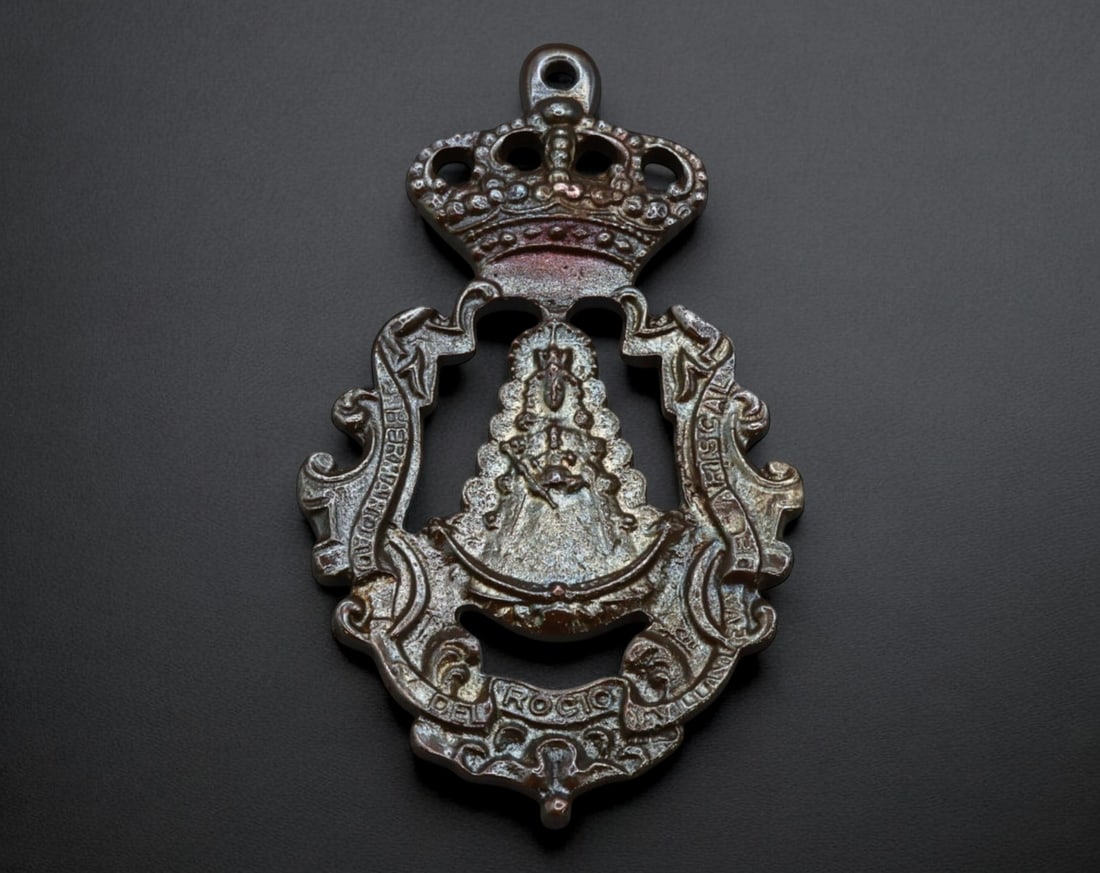 SPAIN: Virgen del Rocio Brotherhood Medal - Bronze, 19th-20th Century: A finely detailed openwork bronze devotional medal, measuring 9.2x5.5 cm and weighing 45g, dedicated to the Virgen del Rocio. The crowned Virgin is prominently depicted at the center, framed by an orn