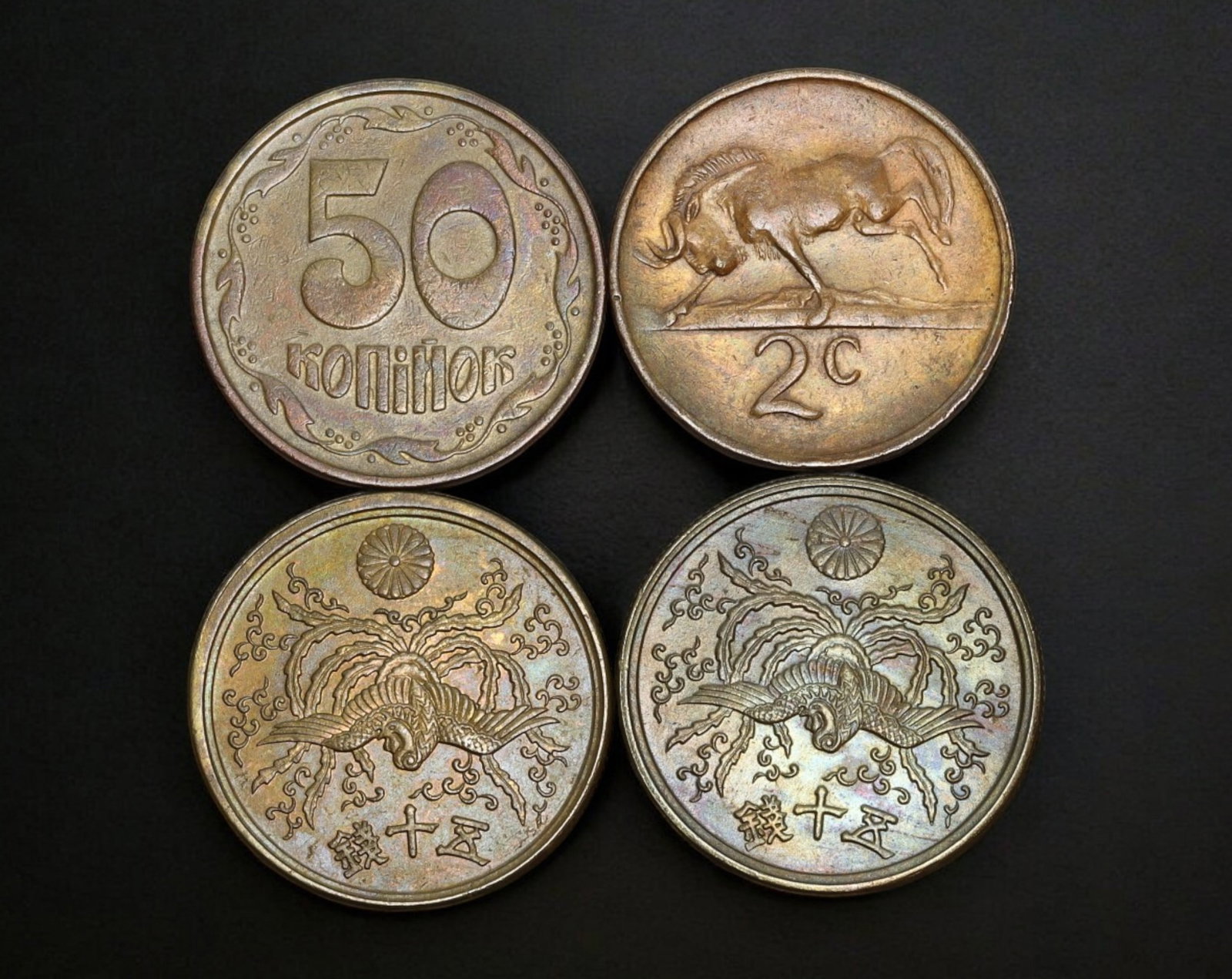 WORLD: Multinational Coin Quartet - Mixed Metals, Japan Showa 21-Ukraine-South Africa, 1946-1992: This four-coin assemblage spans continents and ideologies, weighing 17.2g and measuring 20-22mm each. It includes a 1946 Japanese 50 Sen from Showa Year 21, featuring a wheat sheaf and cogwheel symbol