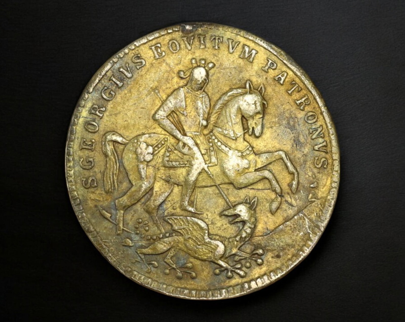 ITALY: St. George & Storm-Tossed Ship Token - Brass Religious Jeton, c.18th Century: This brass devotional jeton, measuring 2.1 cm in diameter and weighing 2.6g, features rich Christian symbolism in striking relief. The obverse presents St. George mounted in full armor, spearing a dra