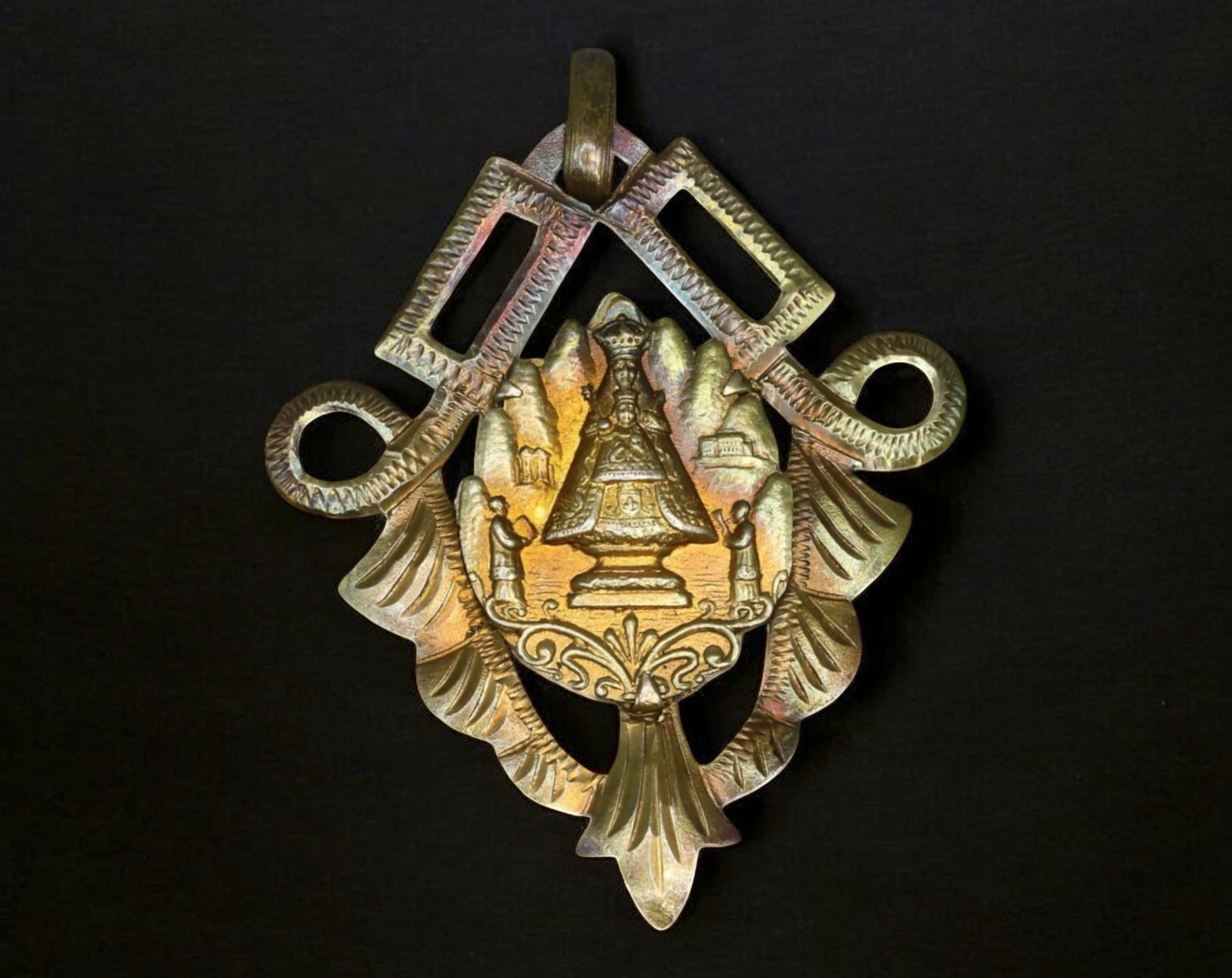 SPAIN: Our Lady of Montserrat Devotional Medal - Ornate Cutout Design: A finely crafted devotional medal honoring Our Lady of Montserrat, featuring an intricate openwork design incorporating stylized elements of Marian devotion. The central motif presents the revered Vir