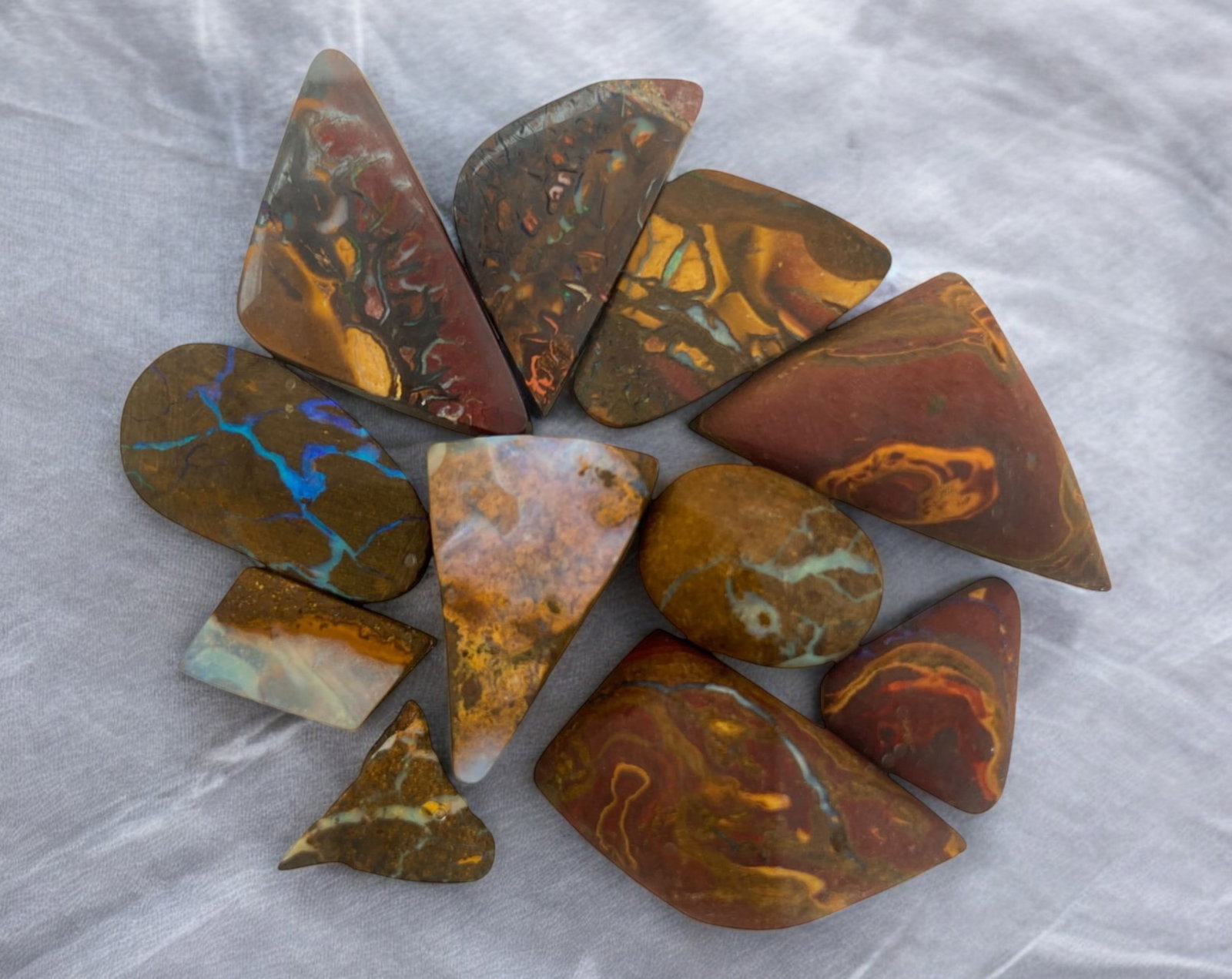 AUSTRALIAN MATRIX BOULDER OPAL - Preform Rough Lot, 11 Pieces, 21.1g, 10-24mm (Images Taken Wet): A dazzling lot of preform Australian matrix boulder opals, with individual sizes. These opals have been rubbed and pre-shaped, highlighting their vibrant natural colors and intricate ironstone matrix 