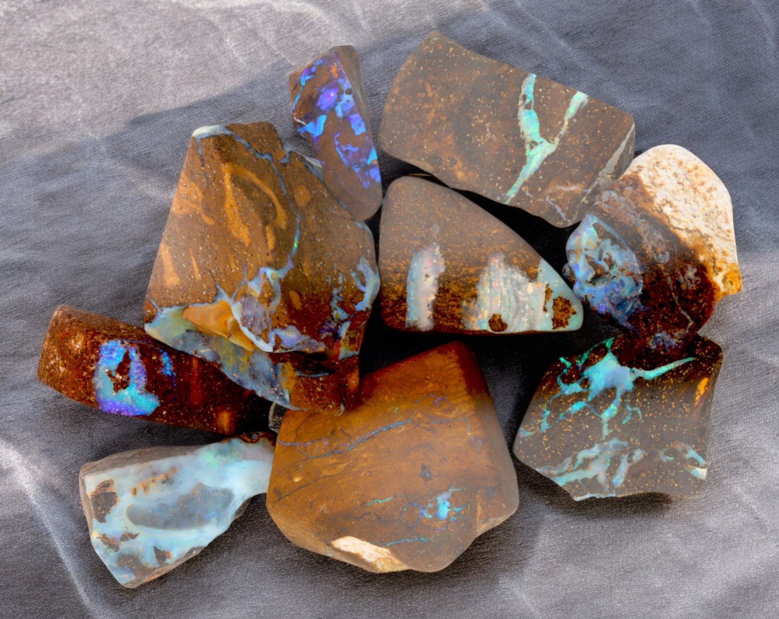 AUSTRALIAN MATRIX BOULDER OPAL - Rough Lot, 33g, 1-2.6cm (Images Taken Wet): A striking lot of natural Australian matrix boulder opal rough. These raw specimens display mesmerizing flashes of blue, green, and gold veins running through ironstone, characteristic of high-quality