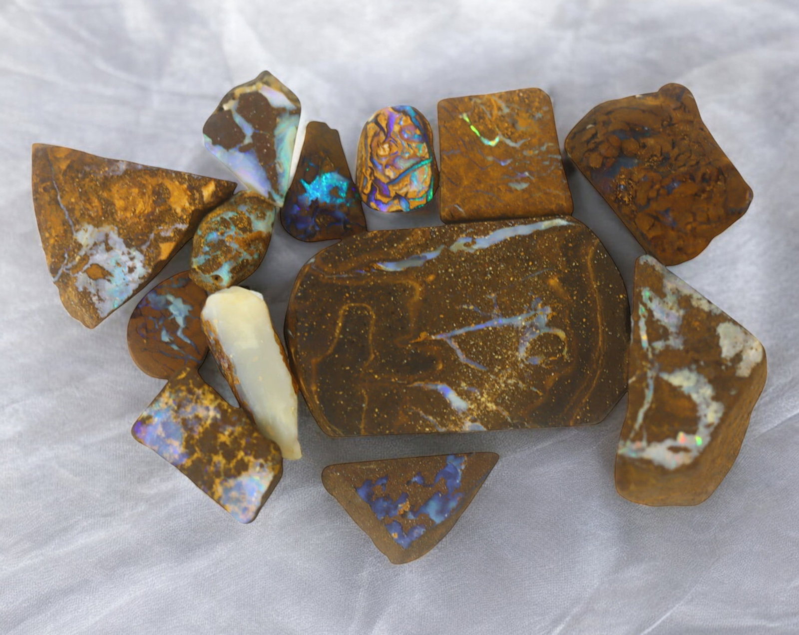 AUSTRALIAN MATRIX BOULDER OPAL - Rough Lot, 44g, 1-3.7cm (Images Taken Wet): A striking lot of natural Australian matrix boulder opal rough. These raw specimens display mesmerizing flashes of blue, green, and gold veins running through ironstone, characteristic of high-quality