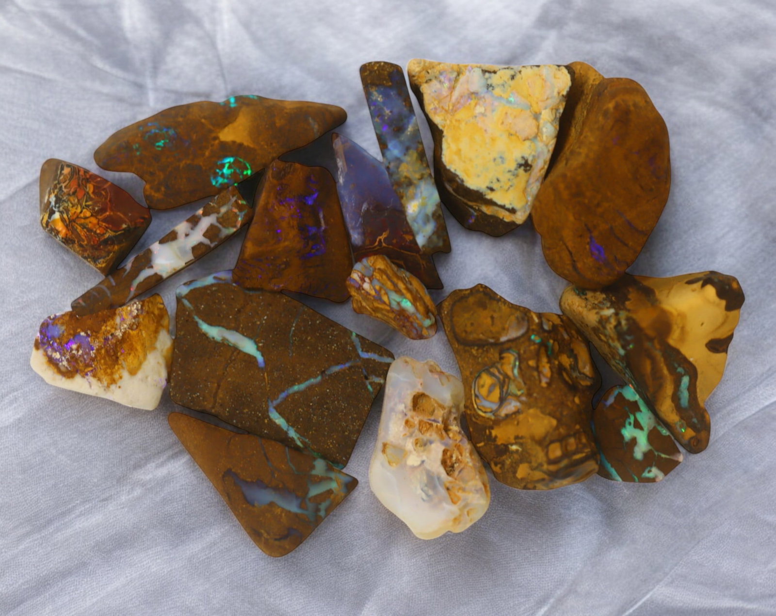 AUSTRALIAN MATRIX BOULDER OPAL - Rough Lot, 38g, 1-2.2cm (Images Taken Wet): A striking lot of natural Australian matrix boulder opal rough. These raw specimens display mesmerizing flashes of blue, green, and gold veins running through ironstone, characteristic of high-quality