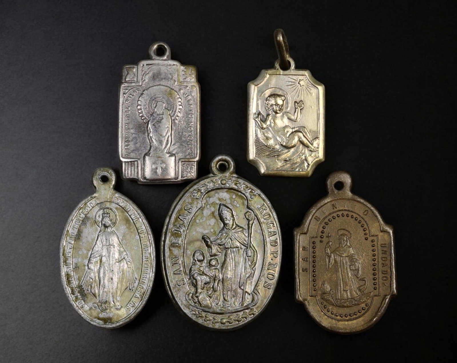 SPAIN: Set of Five Religious Medals - Aluminum & Silvered Metal, 19th-20th Century: A finely detailed set of five religious medals, crafted in aluminum and silvered metal, measuring 1.8 to 2.5 cm and weighing a total of 9g. This collection features representations of the Virgin Mary,