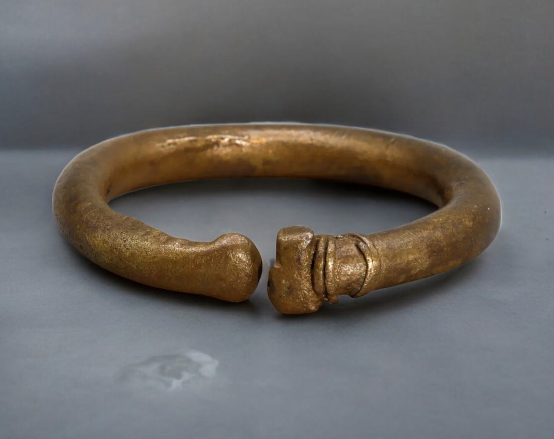 AFRICA: Bronze Currency Bracelet - West African Trade Money, 83g, 6.5x0.8cm: A solid bronze currency bracelet from West Africa, likely used as a form of traditional trade money in the 18th-19th century. Featuring a heavy, rounded form with a slightly tapered, knobbed terminal,