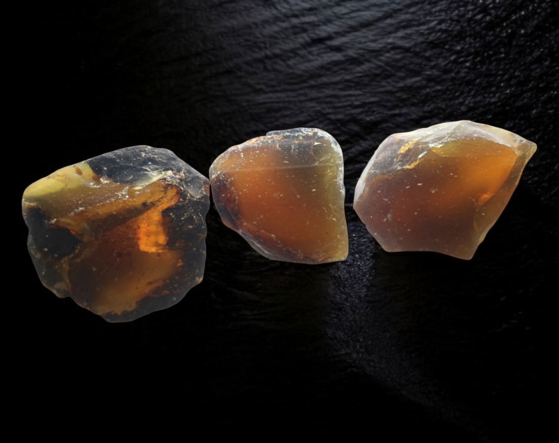 NATURAL: Baltic Amber Specimen Trio - 103g, 4-5cm, Fossilized Tree Resin: A stunning trio of raw Baltic amber specimens, these unpolished pieces display rich golden hues with deep brown inclusions, characteristic of high-quality fossilized tree resin. The translucency and n