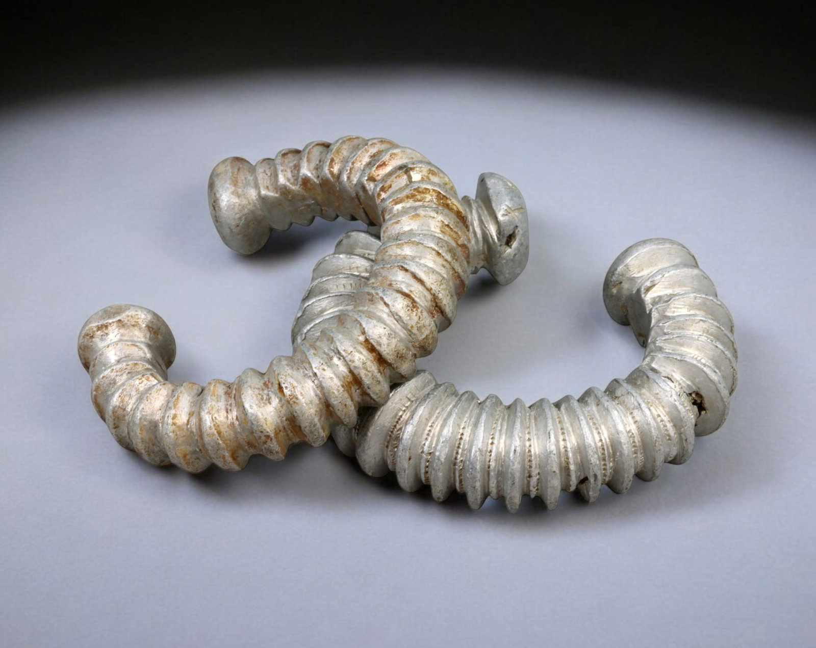 WEST AFRICA: Fulani & Bamileke Ribbed Aluminum Currency Bracelets - 8.2-8.7cm, 209g, 19th/20th C.: A remarkable pair of Fulani and Bamileke aluminum currency bracelets, featuring deeply incised ribbed designs and prominent rounded terminals, reflecting their historical role in wealth storage, dowry