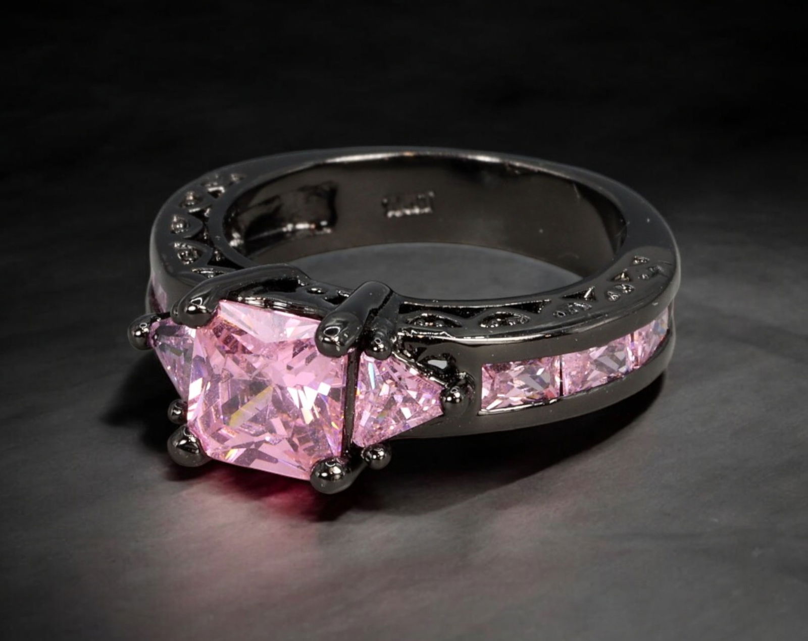 RETRO MODERN: Ring - Blackened Setting with Pink Princess-Cut Stones, US Size 6.75 (6g): A bold Retro Modern ring showcasing a striking blackened metal setting with a central pink princess-cut stone flanked by matching triangular cuts and channel-set square stones along the shank. The viv