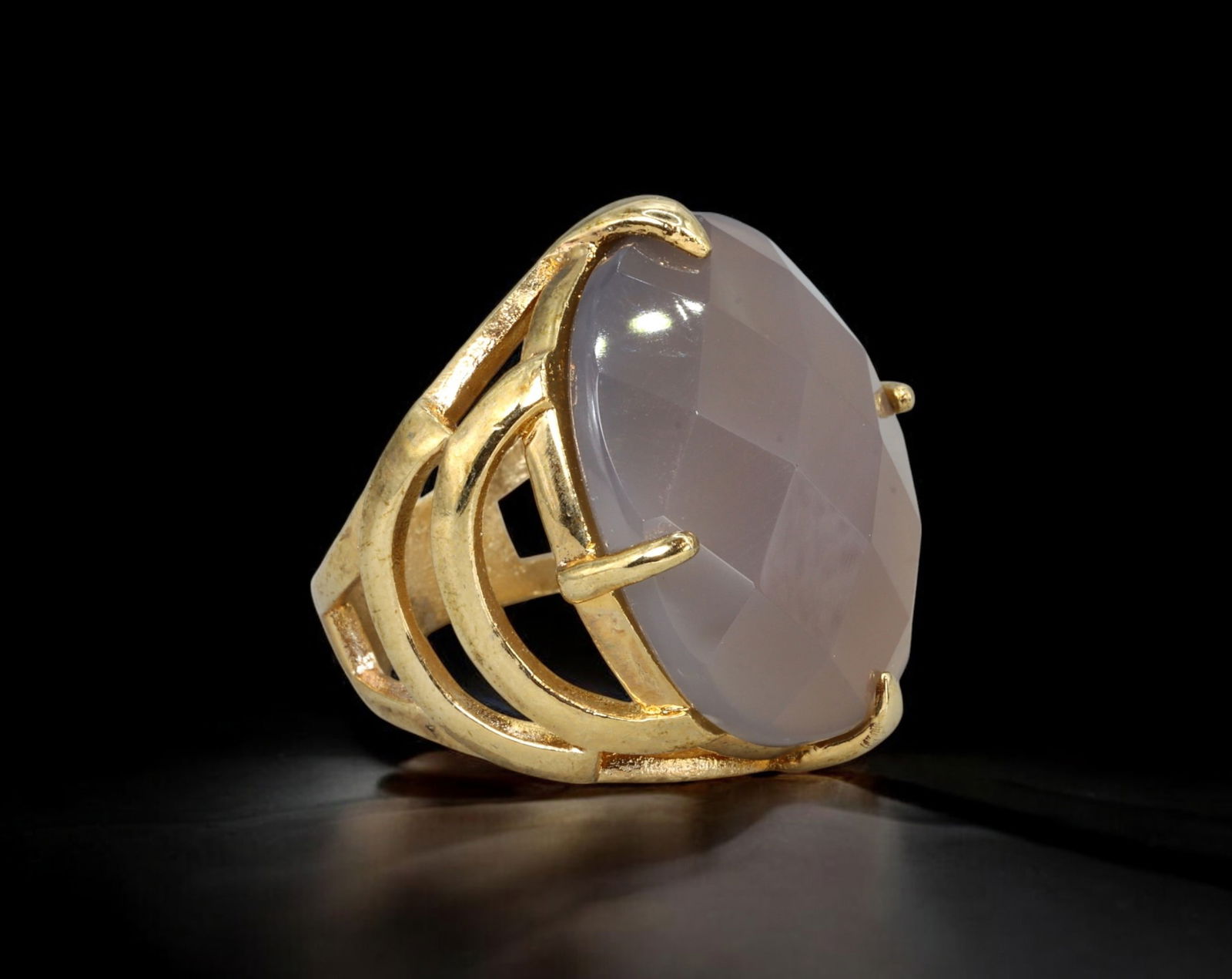 RETRO MODERN: Cocktail Ring - Gold-Tone with Faceted Grey Chalcedony/Onyx, US 8 (17g): A luminous Retro Modern cocktail ring centering on a large, faceted oval grey stone-likely chalcedony or onyx-set in a dynamic openwork gold-tone frame. The arched prong setting echoes the stone's gen