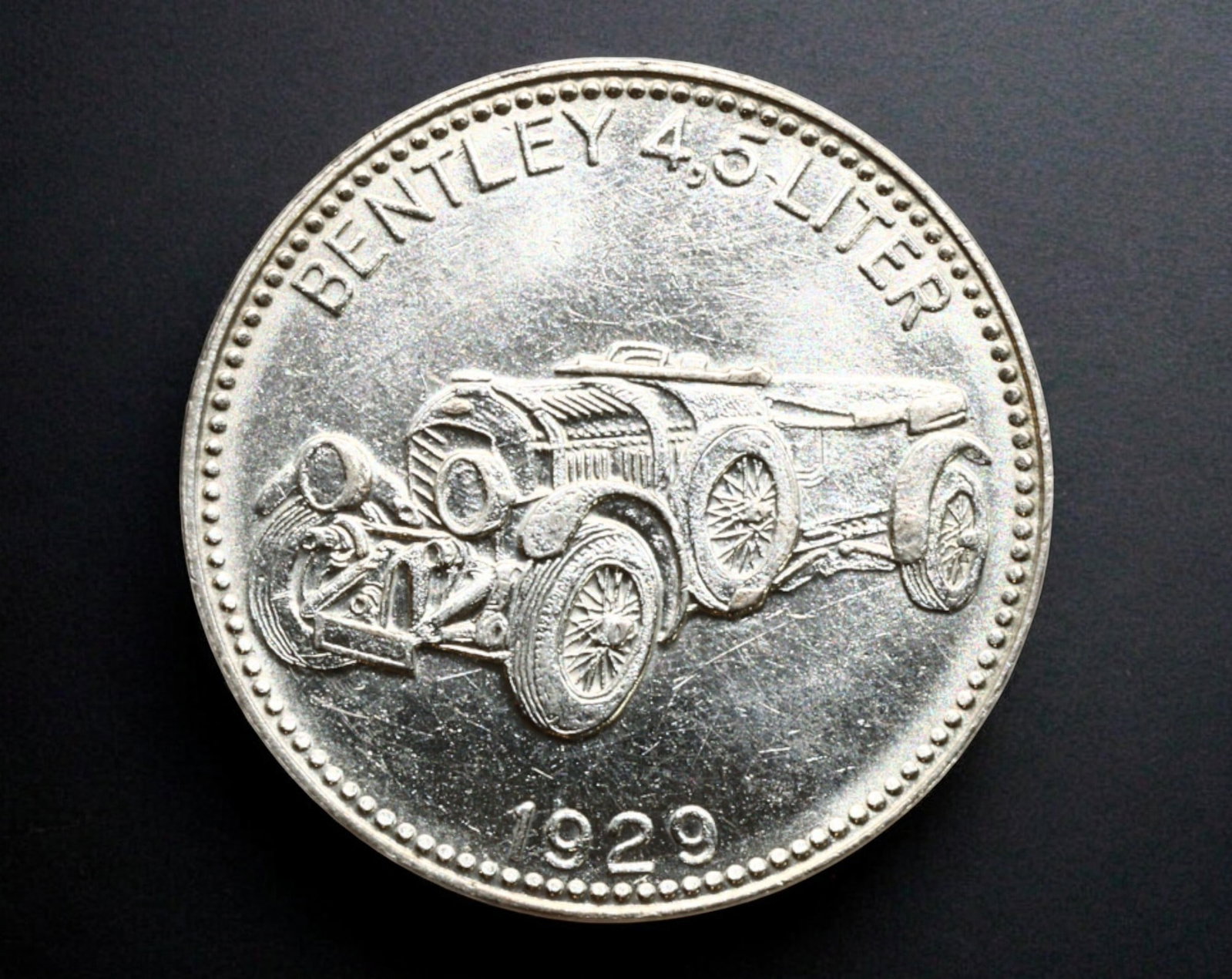GERMANY: Bentley 4.5 Litre "Shell - WELTBERUHMTE Sportwagen" Promotional Token, 1929: A vintage automobile-themed promotional token, struck in a silver-colored alloy, measuring 29mm in diameter and weighing 10g. The obverse features a finely detailed engraving of the legendary Bentley 