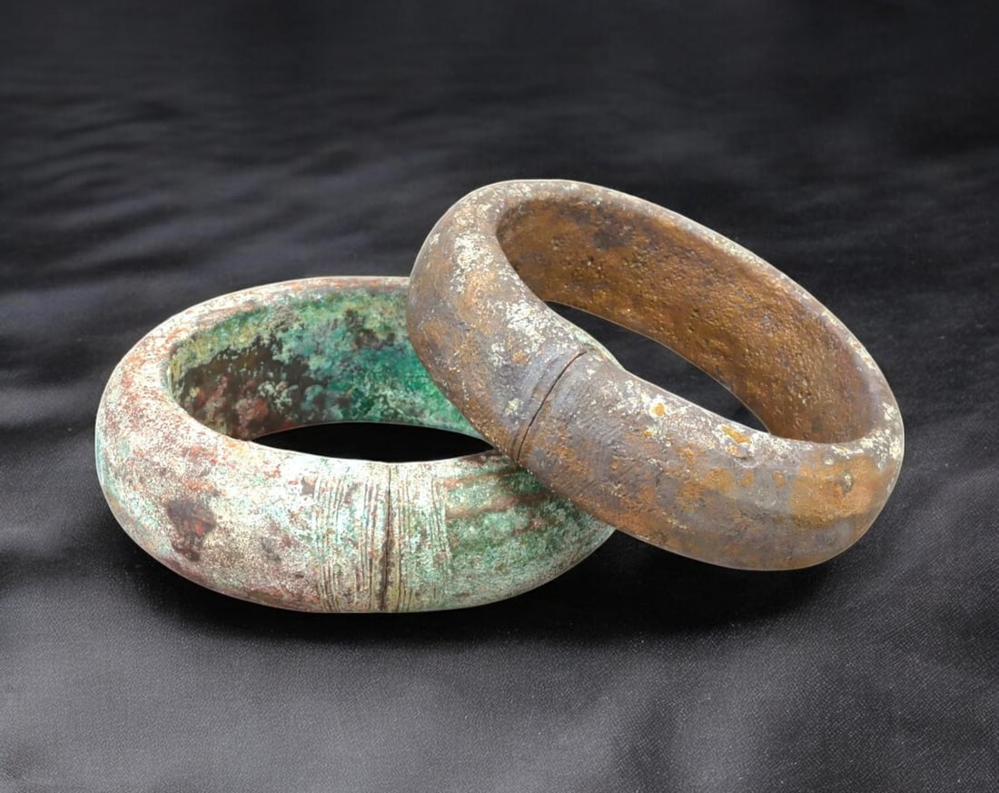 WEST AFRICA: Pair of Heavy Bronze Currency Bracelets - 17th-19th Century: A substantial pair of bronze currency bracelets, each measuring approximately 7.8 x 8 cm with a combined weight of 648g, displaying a rich, aged patina with areas of verdigris and oxidation. These thi