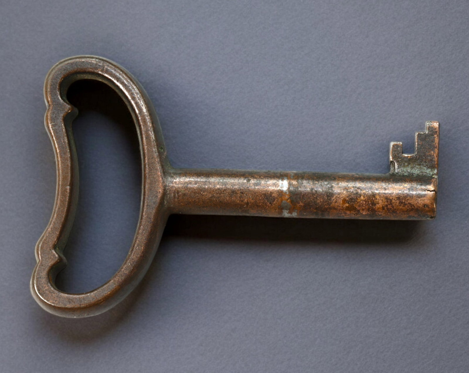 EUROPE: Early 20th Century - Iron Barrel Key, Stepped Bit with Hollow Grip Bow (51mm x 35mm, 18g): Manufactured in iron during the early 20th century, this compact yet robust barrel key features a minimalist, scalloped-edge bow designed for durability and ease of handling. Measuring 51mm in length 