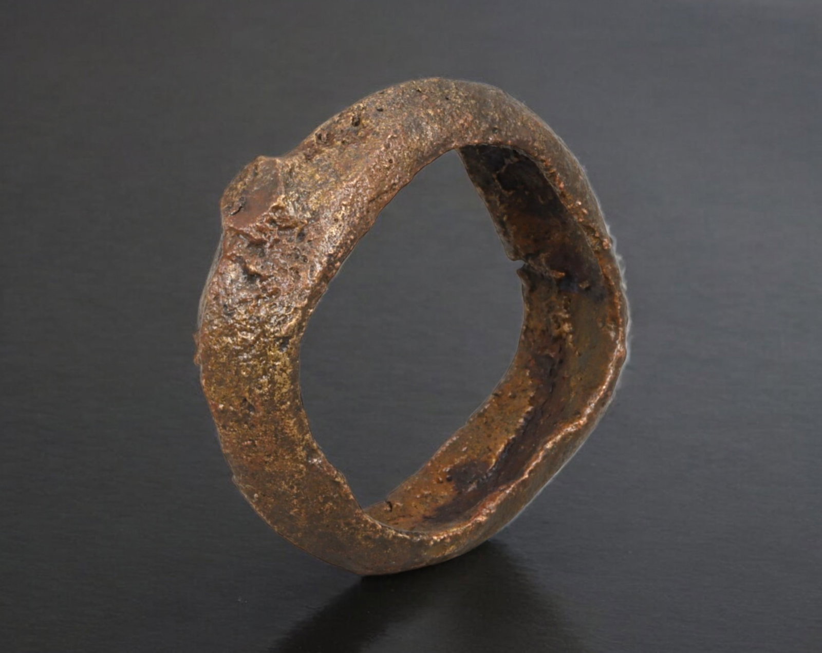 CELTIC PROTO-RING: Trade Ingot - Cast Bronze with Irregular Profile, Continental Europe, 800-400: This 3 cm diameter proto-ring, cast in solid bronze and weighing 15 grams, is a compact example of early prehistoric currency used by Celtic cultures during the Late Bronze to Early Iron Age. Its irre
