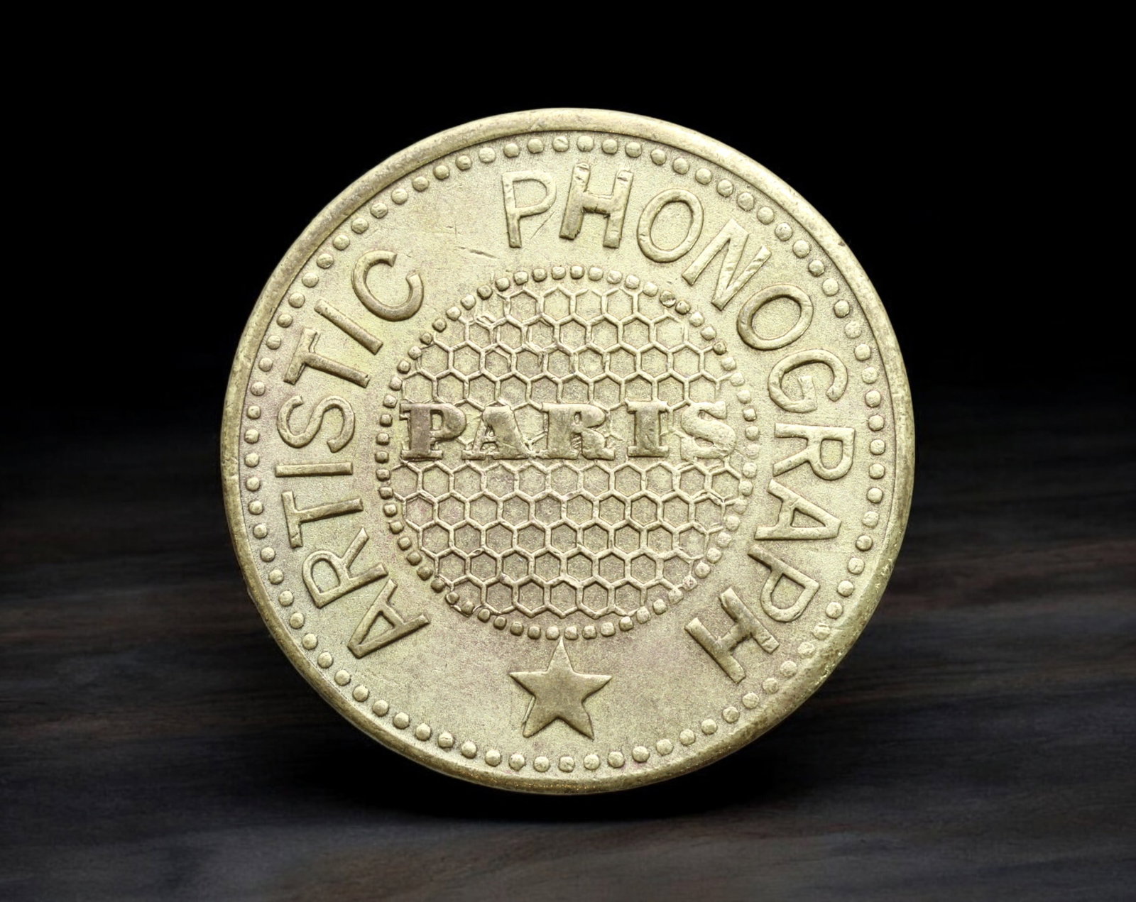 FRANCE: Paris - Brass 1 Hearing Phonograph Token, Artistic Phonograph, ND (23mm, 3.7g): Issued in early 20th-century Paris for the "Artistic Phonograph" jukebox-style entertainment machines, this brass token features the word ''PARIS'' prominently set within a honeycomb-patterned field, 