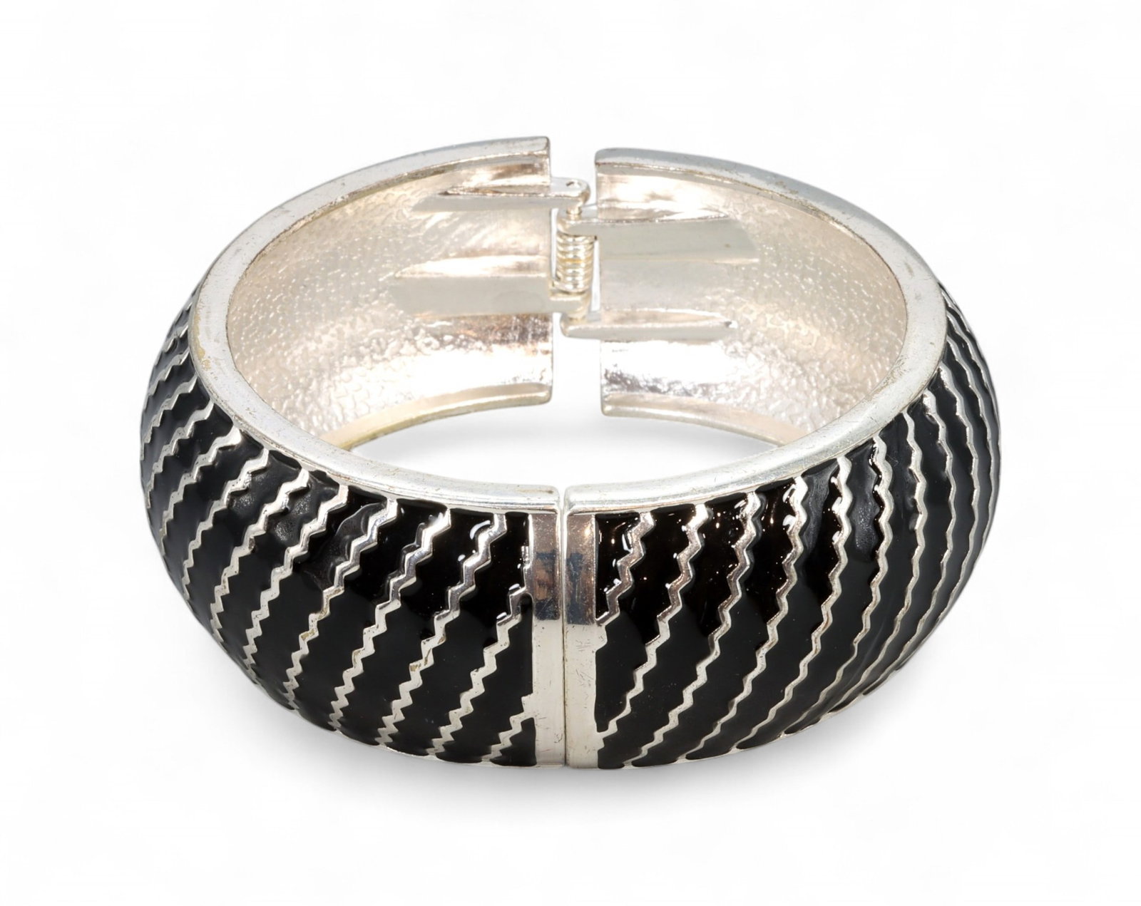 Hinge Bangle - Black & Silvertone Zigzag Enamel, 9cm: This striking hinge bangle features a wide domed silhouette with alternating zigzag enamel detailing in bold black and reflective silvertone. The structured form and glossy surface evoke the high-impa