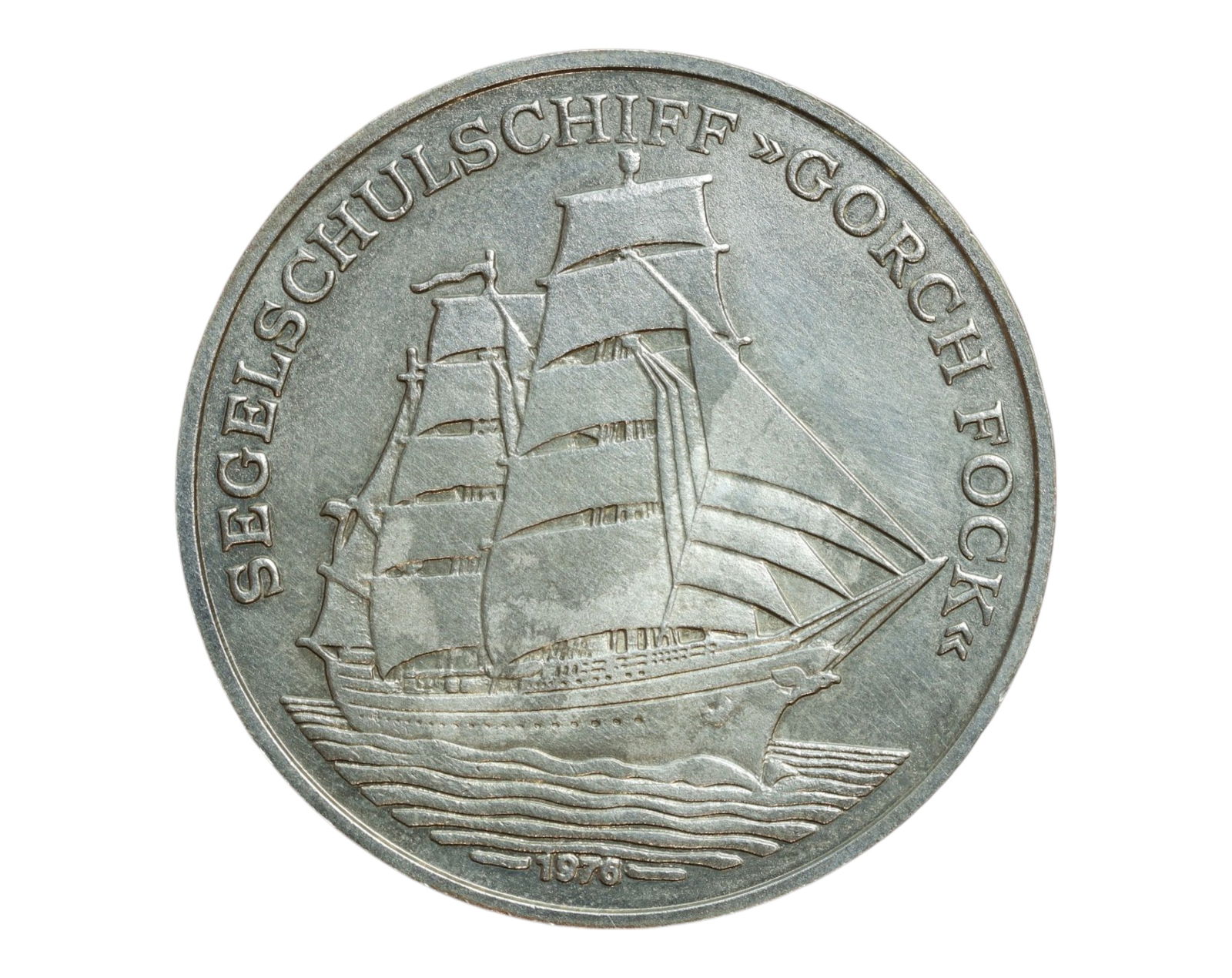 GERMANY: Segelschulschiff Gorch Fock - Seafaring Tribute Token, 1976 (38mm): Issued in 1976, this 38mm maritime token honors the Gorch Fock, the famed German Navy sail training ship launched in 1958 and named after the patriotic poet Johann Kinau. The obverse presents the thre