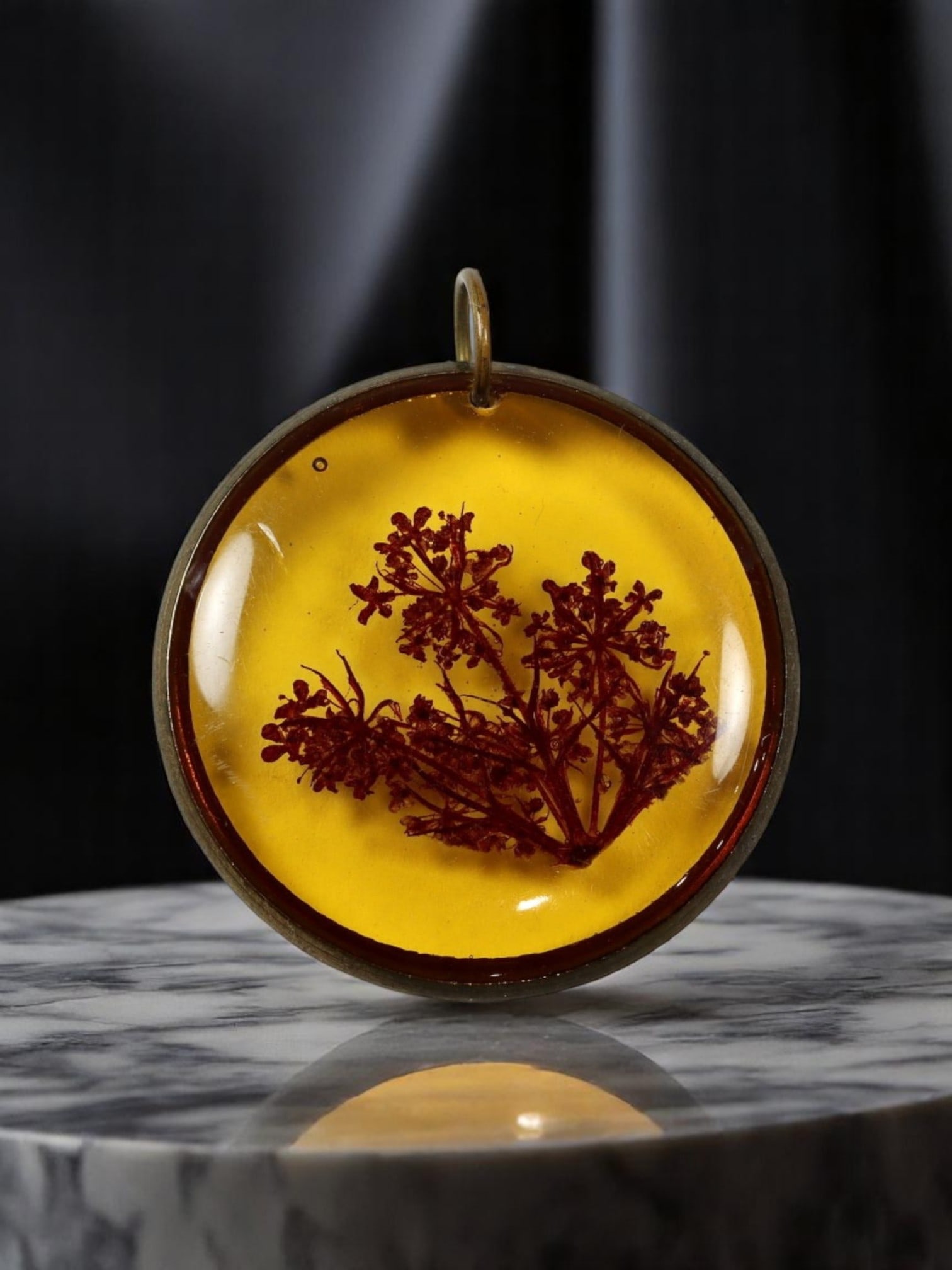 MID-CENTURY: Botanical Resin Pendant - Deep Burgundy Flora in Amber-Tone Dome (3 cm): A moody yet elegant botanical pendant from the mid-20th century, featuring a finely preserved deep burgundy floral sprig embedded in translucent amber-hued resin. The silhouette of the pressed flower