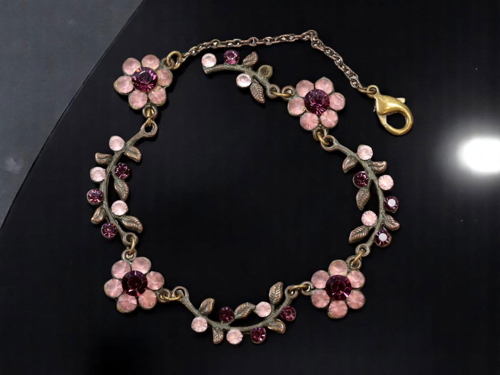 VINTAGE FLORAL REVIVAL: Bracelet - Blush & Amethyst-Tone Crystal Blossoms, 27cm, Repair Needed: Evoking the romantic charm of early 20th-century floral revival styles, this articulated bracelet features a garland of blush and amethyst-tone crystal blossoms with leaf-textured metalwork in an anti