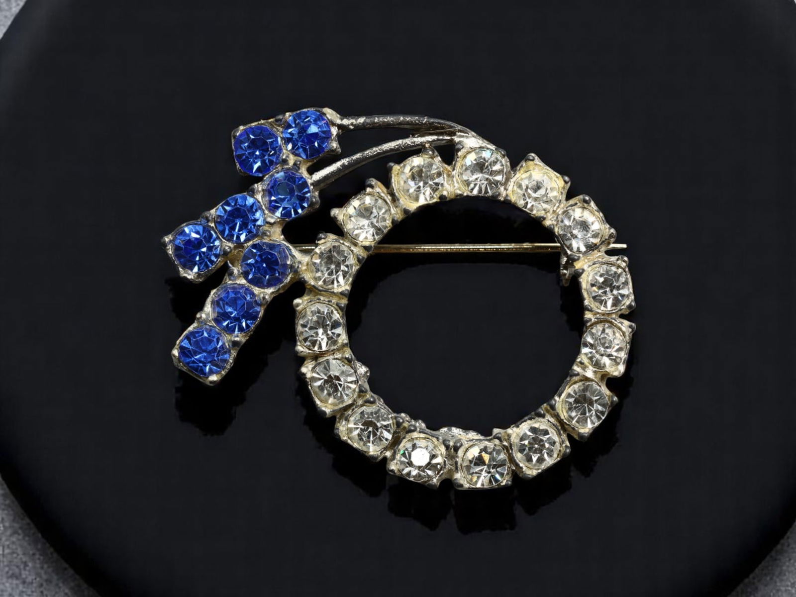 BOLD STATEMENT ERA: Venus Symbol Brooch - Clear & Sapphire-Blue Brilliant-Cut Gems, 4x3cm: A dazzling tribute to feminine strength, this circular Venus symbol brooch commands attention with alternating clear and sapphire-blue brilliant-cut stones, all prong-set in a radiant silvertone frame