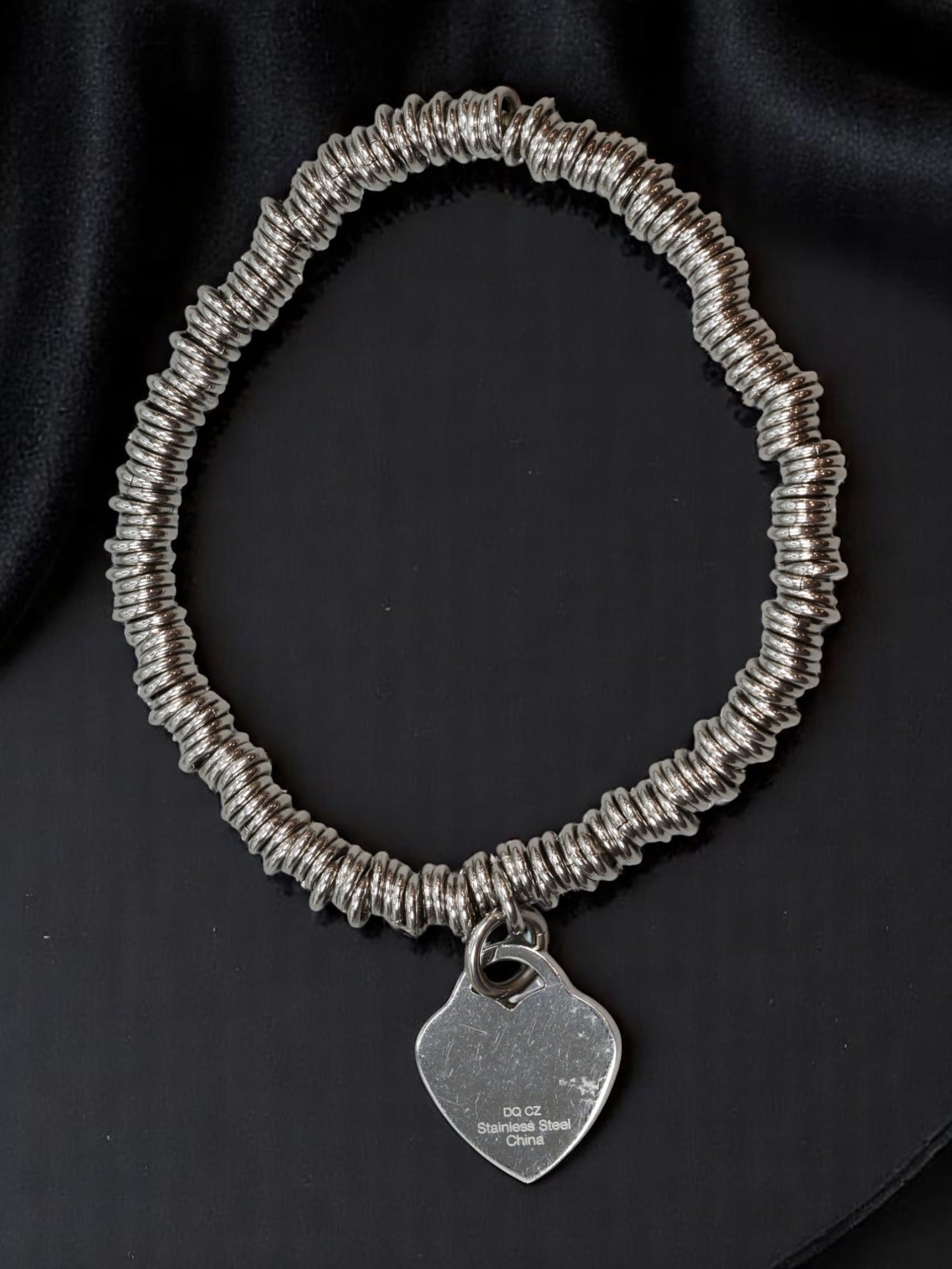 CONTEMPORARY: Coil Ring Bracelet - Stainless Steel Tone with Heart Charm (20cm): A modern, edgy bracelet crafted with densely stacked stainless steel-tone rings on a stretch-fit band, completed by a polished heart-shaped charm. The sleek industrial look, paired with the sentimenta