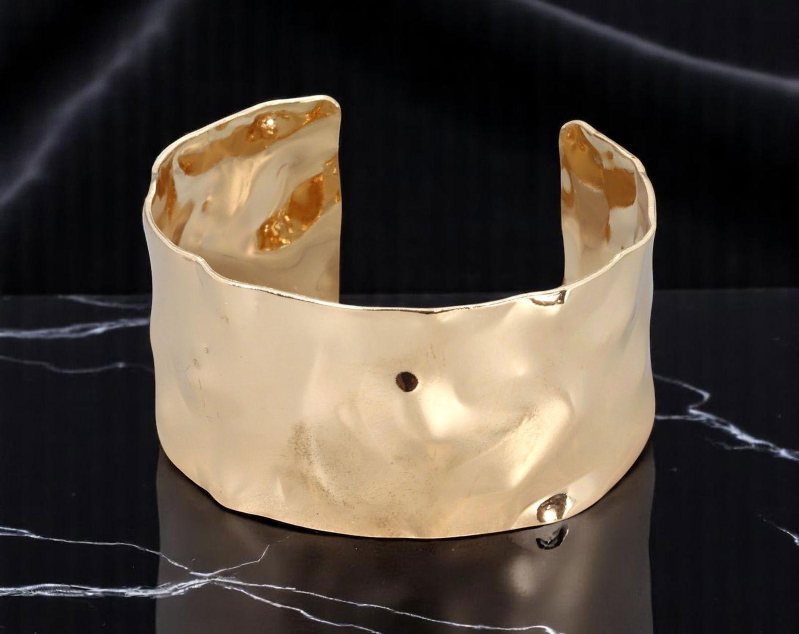 Wide Cuff - Hammered Form, Fluid Edge, Goldtone (6.5cm): A bold and expressive wide cuff bracelet in radiant goldtone, this piece features a hand-hammered style texture with fluid, organic edges. Its undulating form captures light across a sculptural surfac