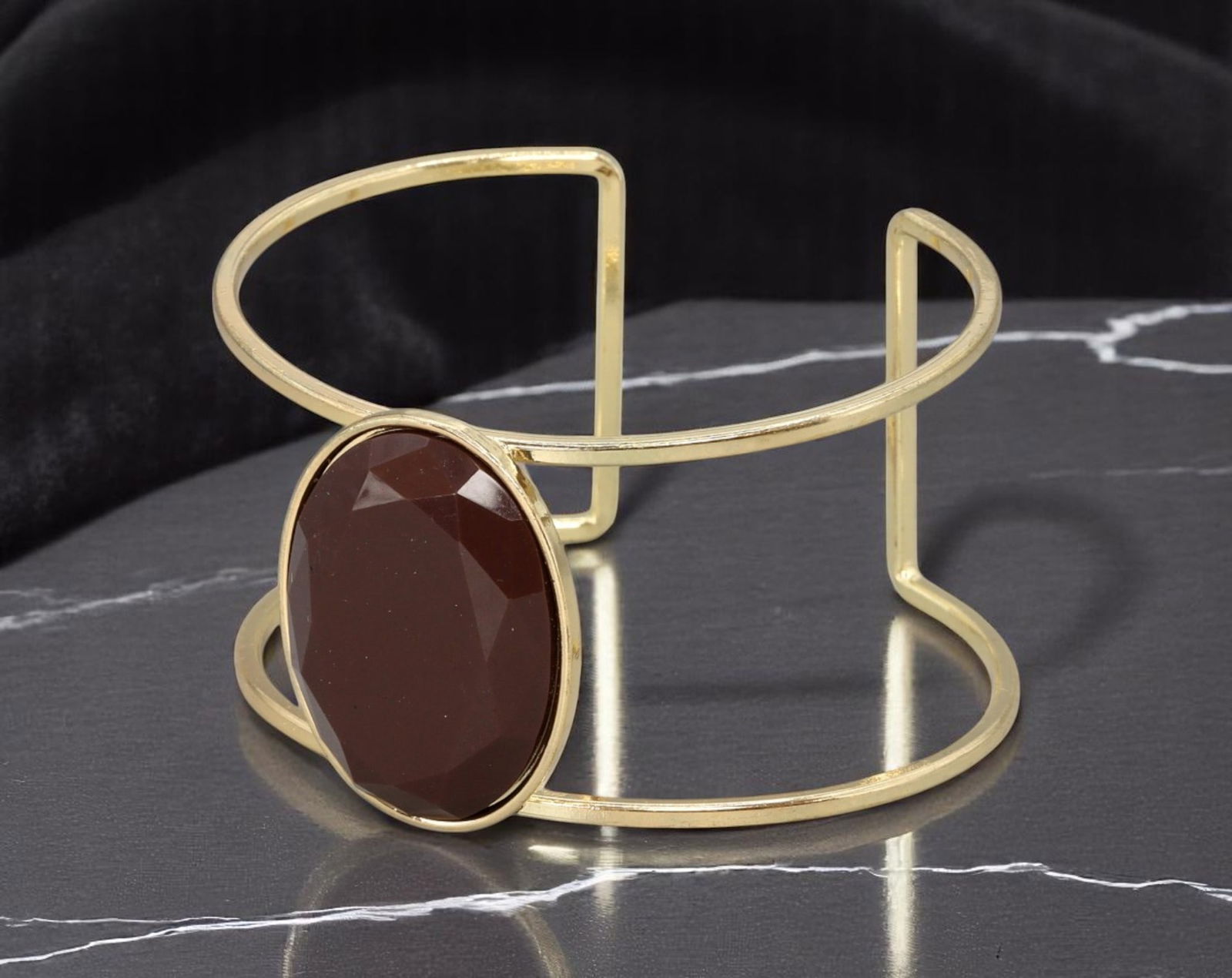 Cuff Bracelet - Open Frame with Faceted Brown Stone, Goldtone (6.5cm): This sleek, open-frame cuff bracelet features a geometric double-band structure in polished goldtone metal, anchored by a large oval faceted center stone in a deep cocoa brown hue. The minimal framing