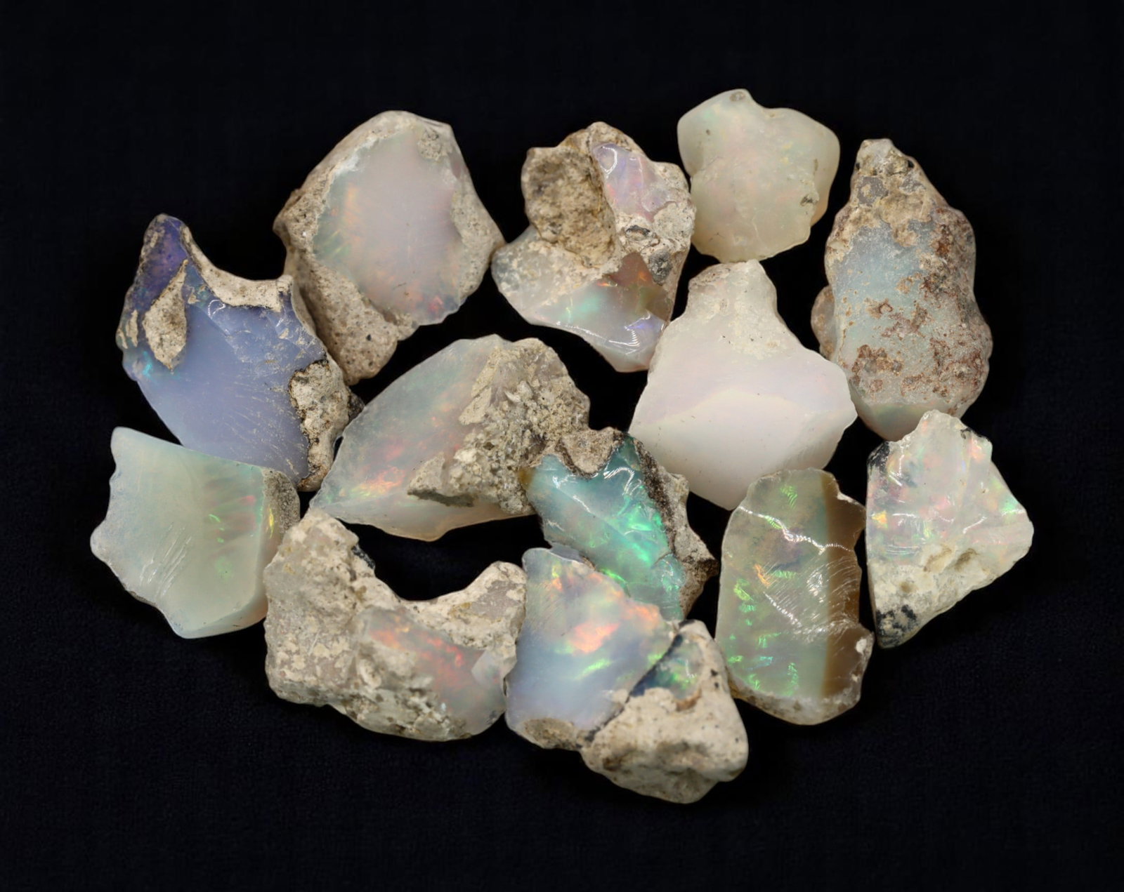 GEM LOT: Ethiopian Welo Opal Rough - Iridescent Play-of-Color in Matrix, Mixed Forms (13g): An estate-sourced parcel of natural Ethiopian Welo Opal rough, totaling 11 grams, this lot features raw, matrix-hosted specimens with vibrant play-of-color across milky, translucent, and honey-toned b