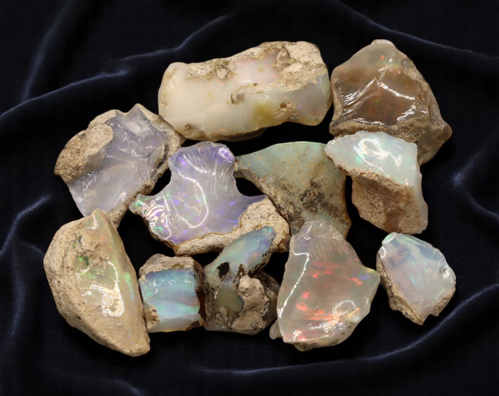 GEM LOT: Ethiopian Welo Opal Rough - Iridescent Play-of-Color in Matrix, Mixed Forms (13g): An estate-sourced parcel of natural Ethiopian Welo Opal rough, totaling 11 grams, this lot features raw, matrix-hosted specimens with vibrant play-of-color across milky, translucent, and honey-toned b