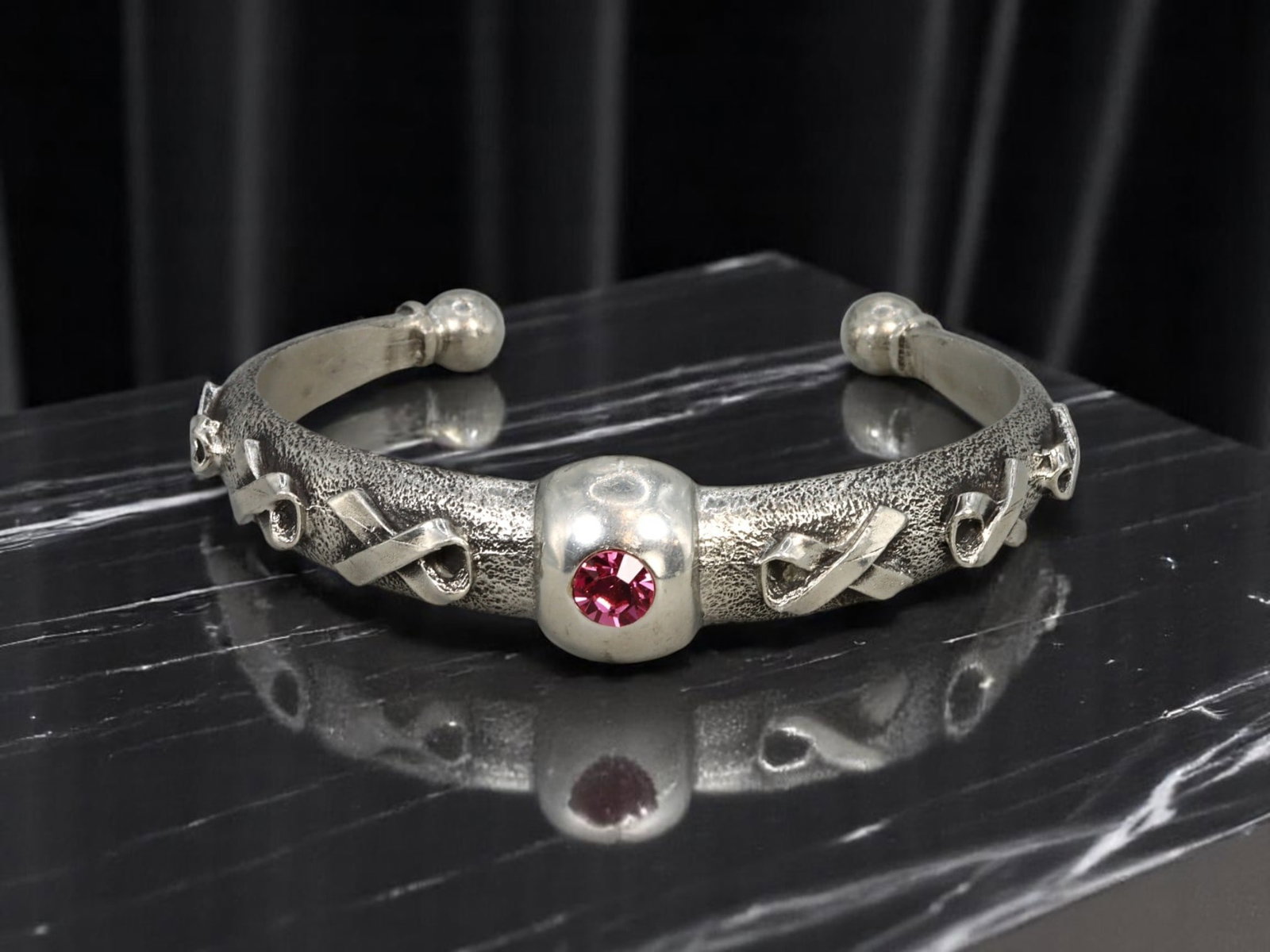 ARTISTIC MODERN STYLE: Bangle Bracelet - Sculptural Ribbon Motif, Pink Stone Accent, 7x1.7cm, 42g: A bold and symbolic estate bangle bracelet rendered in sculptural silvertone, this 7 x 1.7 cm piece features a textured surface adorned with dimensional ribbon motifs in repeating relief. At the cente