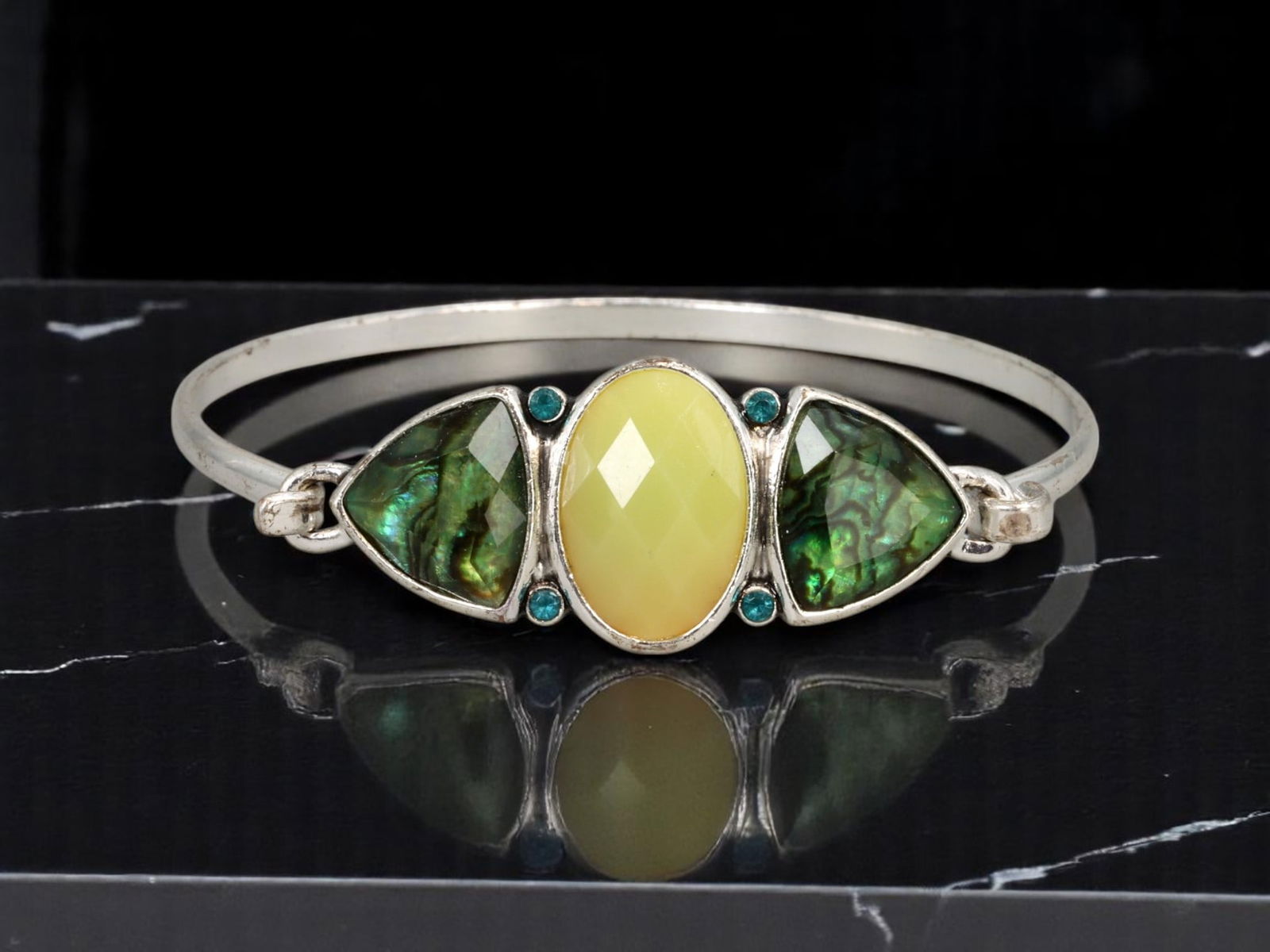 ARTISTIC MODERN STYLE: Hinged Bangle - Faceted Yellow Center Stone with Abalone-Like Inlays, 6cm: A visually striking estate bangle in silvertone metal, this 6 cm hinged bracelet centers on a faceted yellow oval stone flanked by luminous abalone-like inlays in triangular bezels. Four teal accent s