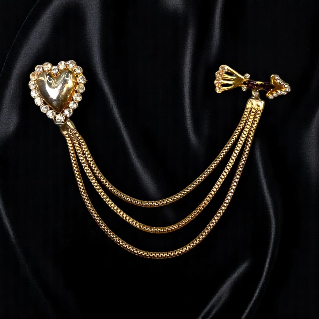 Brooch - Heart & Bow Motifs, Clear Stone Accents, Draped Goldtone Chains 26cm: From an estate jewelry collection, this modern romantic brooch blends playful elegance with bold design. A polished heart motif surrounded by brilliant-cut clear stone-like accents pairs with a sculpt
