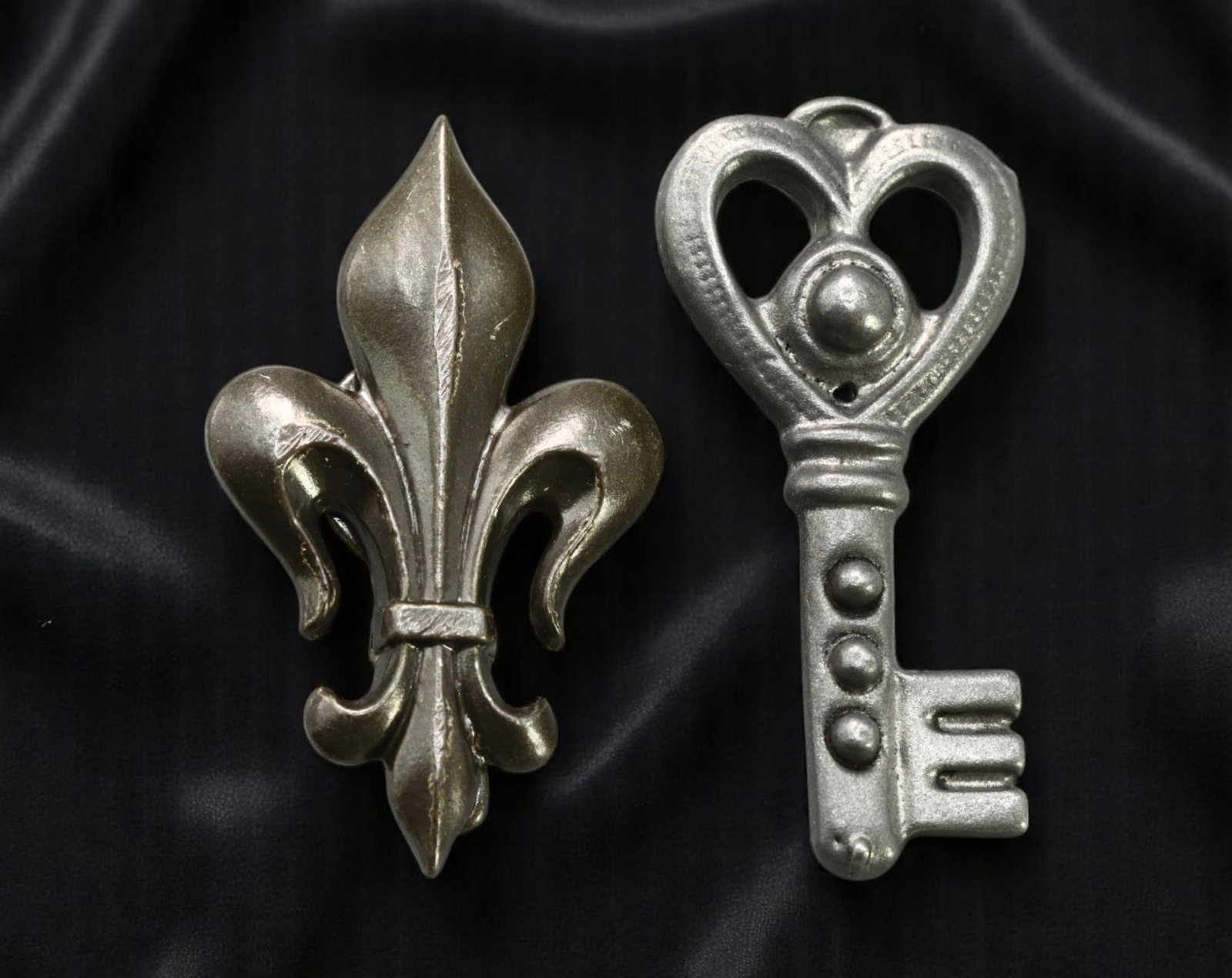 Brooch & Pendant Lot - Fleur-de-Lis Brooch, Heart Key Pendant, Silvertone Finish (2pcs, 2.7-3 cm): A distinctive two-piece lot featuring a richly sculpted silvertone fleur-de-lis brooch alongside an oversized heart-topped key pendant with sculptural detailing. Both pieces showcase bold symbolic for