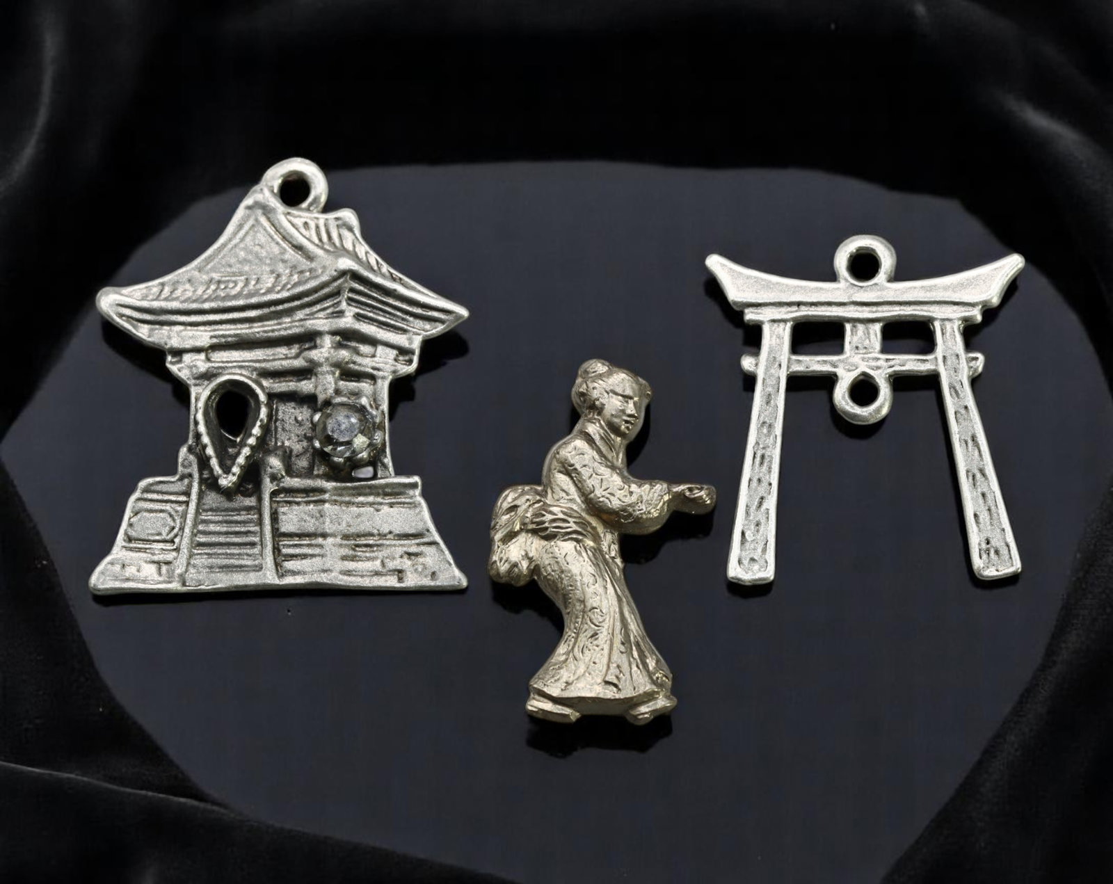 Charm Lot - Asian Temple, Geisha Figure, and Torii Gate Motifs, Silvertone (3pcs, 2.5-3 cm): A distinctive trio of silvertone charms capturing stylized Asian motifs. The lot features a detailed temple charm with an accent clear stone, a sculptural geisha figure in traditional dress, and a min