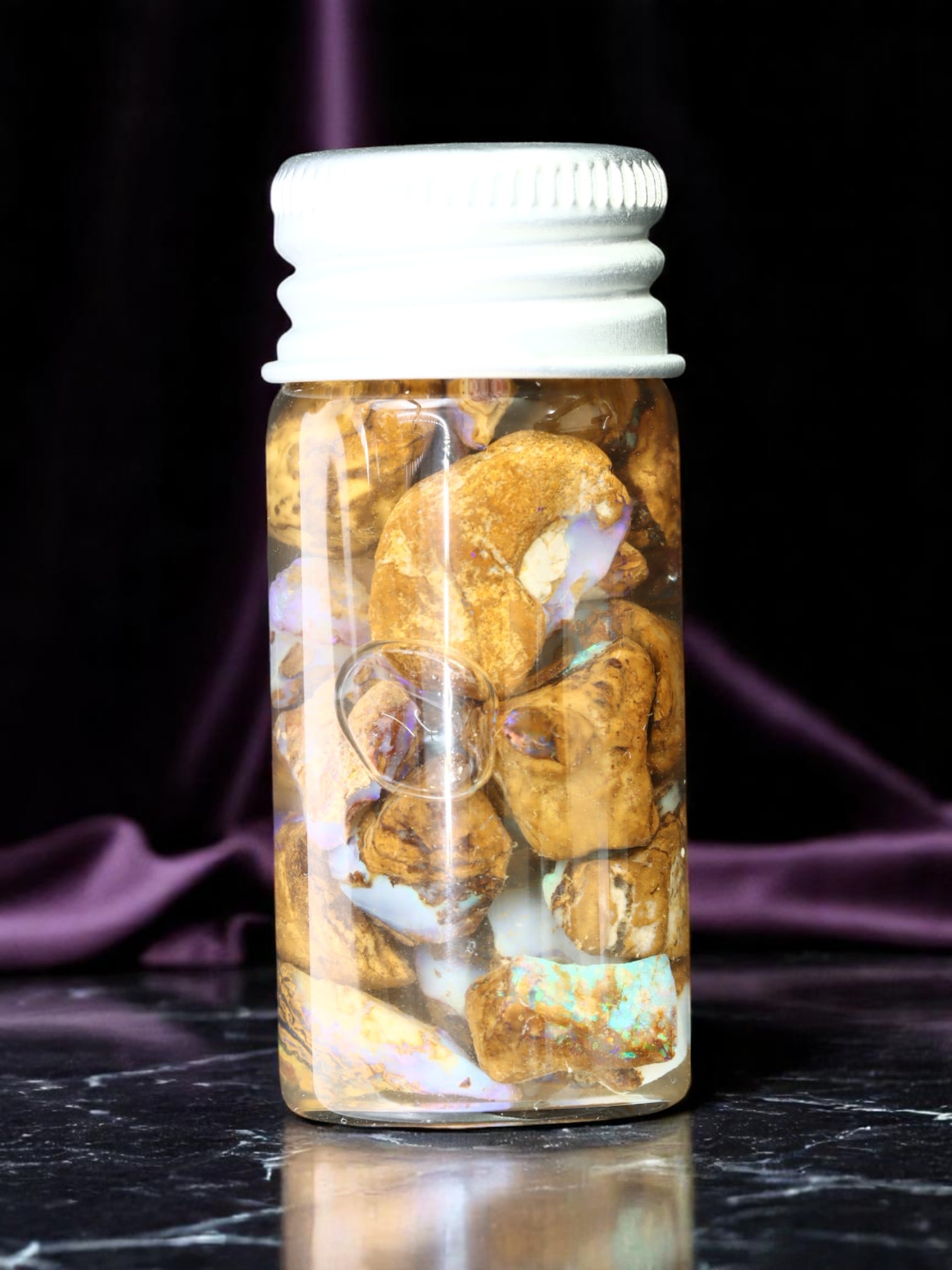 Specimen Jar - Koroit Boulder Opal Rough, Earthtone Matrix & Iridescence (5 x 2 cm): An exceptional collector's specimen jar featuring rough Koroit boulder opal fragments, prized for their distinctive earthtone ironstone matrix interspersed with luminous opal-effect flashes. This comp