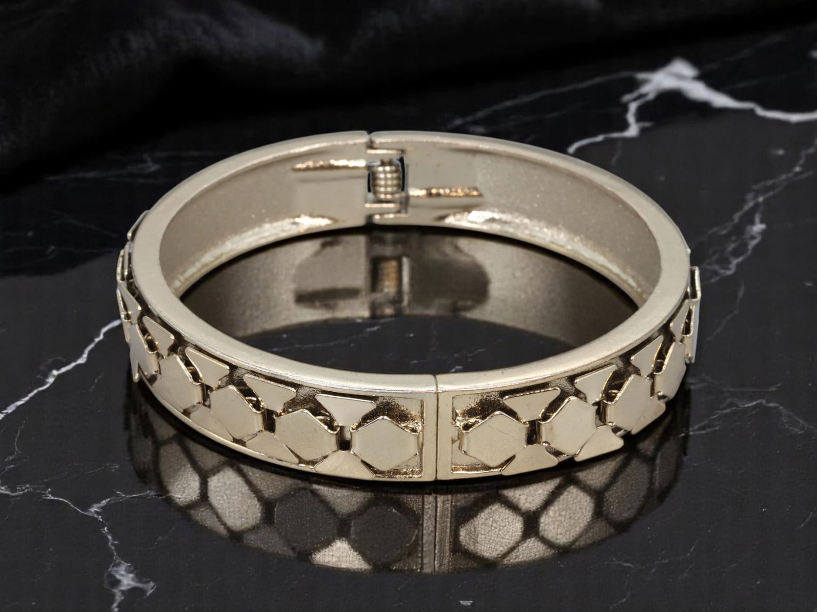 LATE 20TH CENTURY: Estate Hinged Bangle - Goldtone Geometric Link Pattern, 7cm: A striking estate jewelry piece from the late 20th century, this hinged goldtone bangle features a raised geometric link pattern that offers bold texture and dimensional appeal. The polished surface c