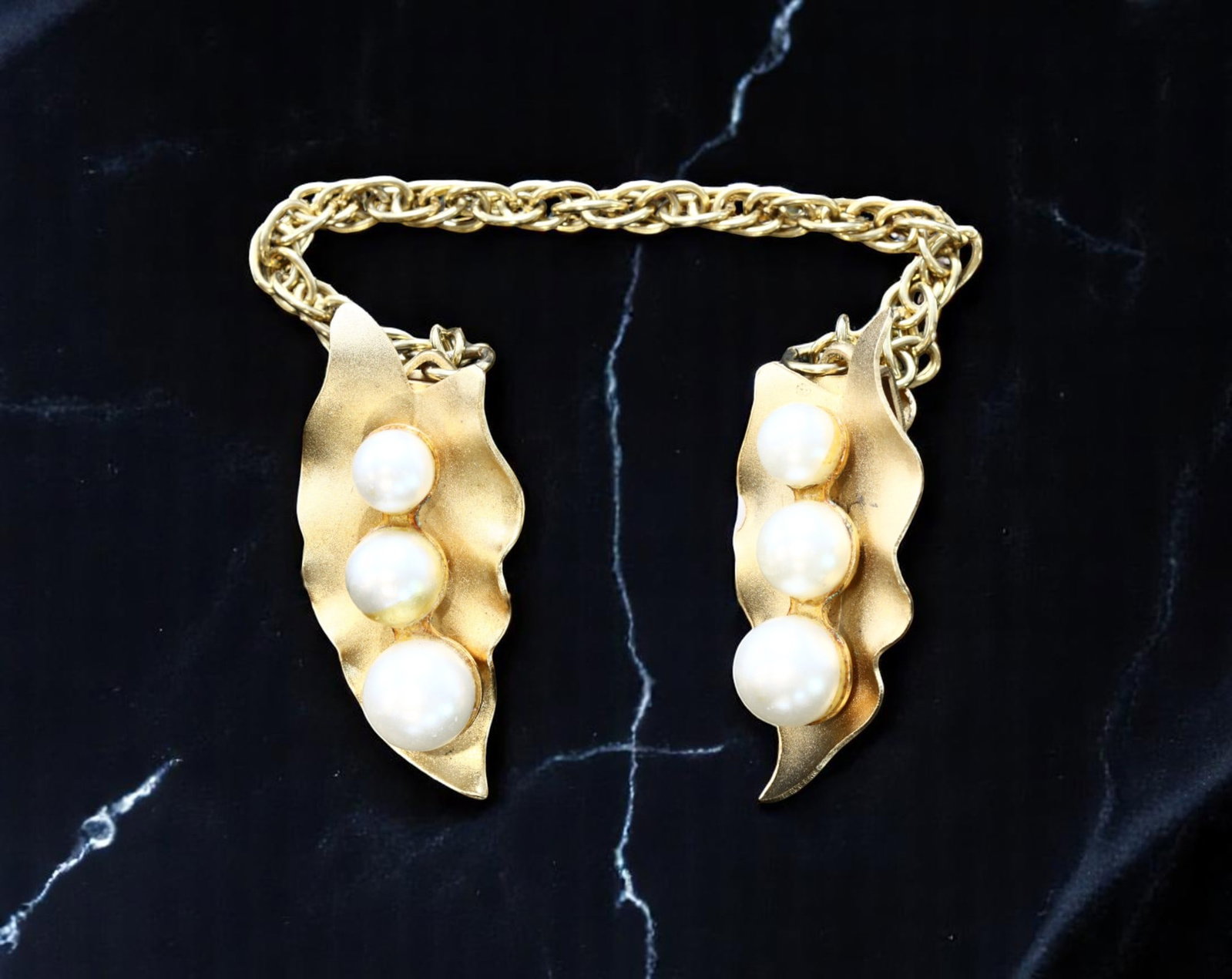 ARTS & CRAFTS MOVEMENT: Double Brooch with Chain - Leaf Pods & Pearl-Like Beads: A rare and sculptural example inspired by the Arts & Crafts Movement, this double brooch design features two leaf pod forms rendered in a softly brushed goldtone finish. Each brooch is accented by thr