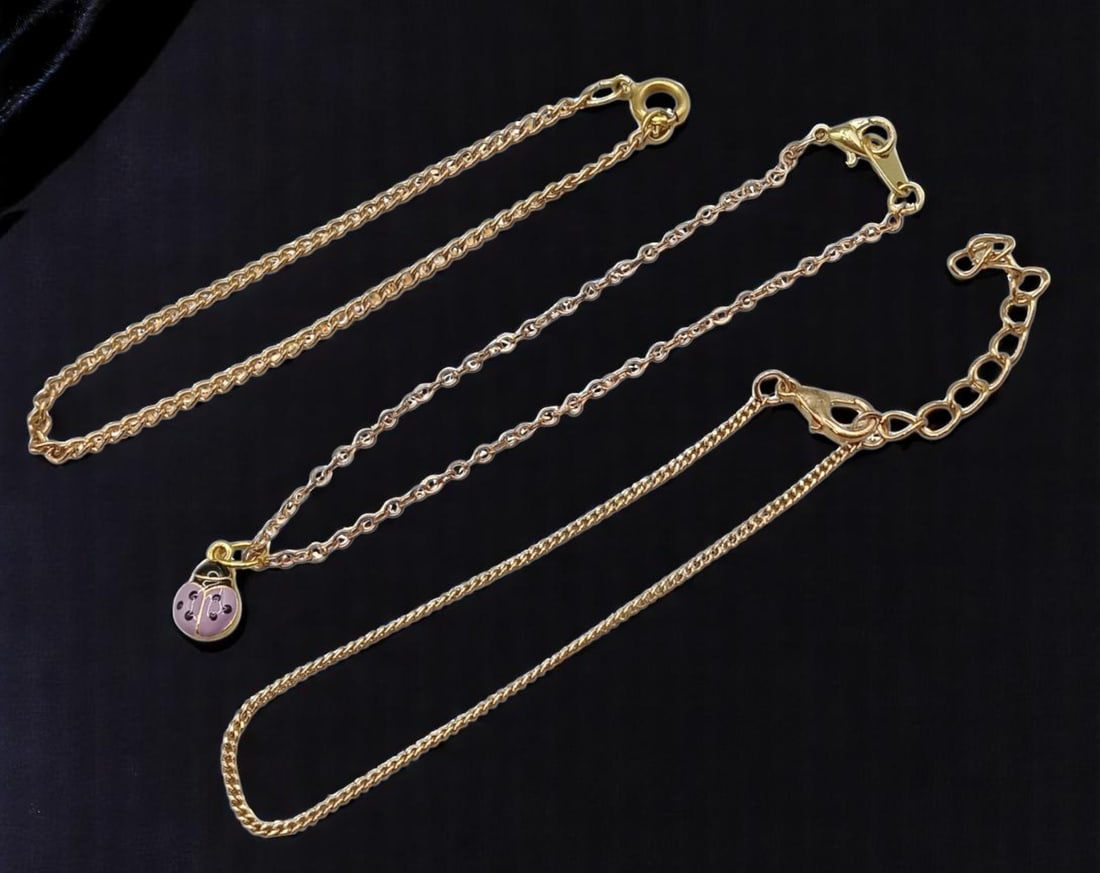 Bracelet Trio - Mixed Goldtone Chains with Ladybug Charm (16 - 20 cm): A playful and stylish set, this trio of contemporary bracelets features three distinct goldtone chain designs, ranging from approximately 16 to 20 cm in length. One bracelet includes a whimsical pink