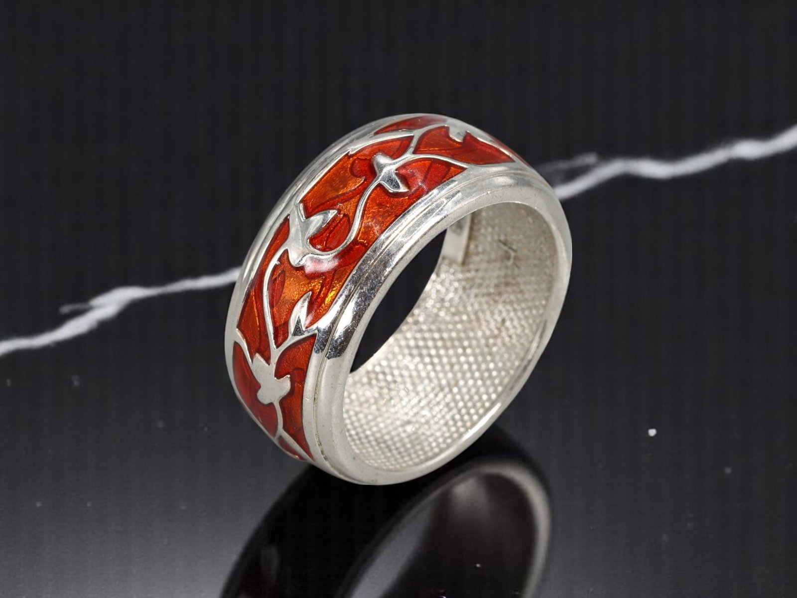 ARTISAN: Wide Band Ring - Sculptural Scroll Motif, Vibrant Red Enamel, US 8: A finely crafted contemporary wide band ring, this piece features an intricate sculptural scrollwork motif rendered in vibrant red enamel-effect inlay against a luminous silvertone backdrop. The textu