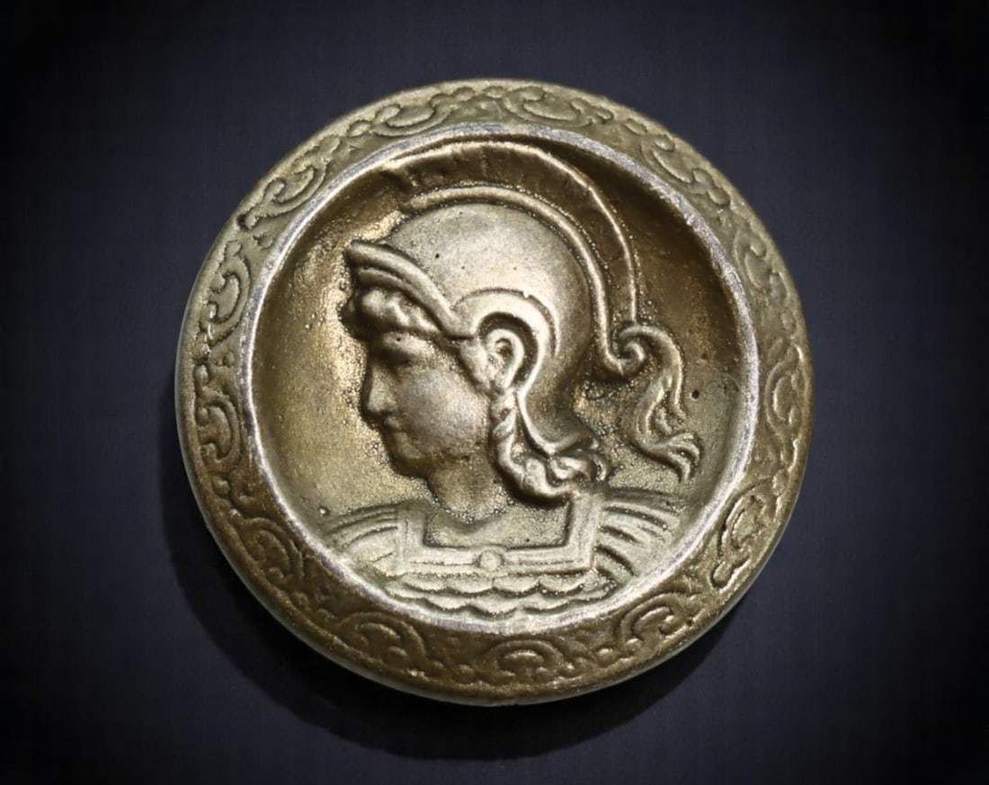 FRANCE: Classical Revival - Helmeted Athena Decorative Button, c.1900s, 18mm: This ornate brass-tone button showcases a neoclassical portrayal of Athena, the Greek goddess of wisdom and warfare, rendered in profile wearing a Corinthian helmet. The high-relief portrait is framed