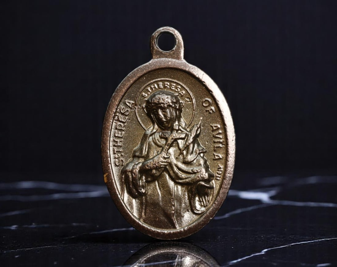 ITALY: Mystical Reformer - St. Theresa of Avila Devotional Medal, ca. Mid-20th Century, 25mm: This devotional medal pays tribute to St. Theresa of Avila, the famed Spanish mystic and Carmelite reformer canonized for her spiritual writings and unwavering devotion. Cast in Italy during the mid-2