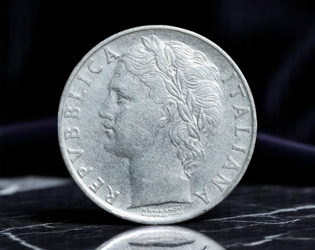 ITALY: Republic - Minerva and Olive Tree 100 Lire Coin, 1957 R Rome Mint (28mm): Struck at the Rome Mint in 1957, this 100 Lire coin showcases the serene authority of Minerva, Roman goddess of wisdom and strategic warfare, as she reaches toward an olive tree-symbolizing peace and 