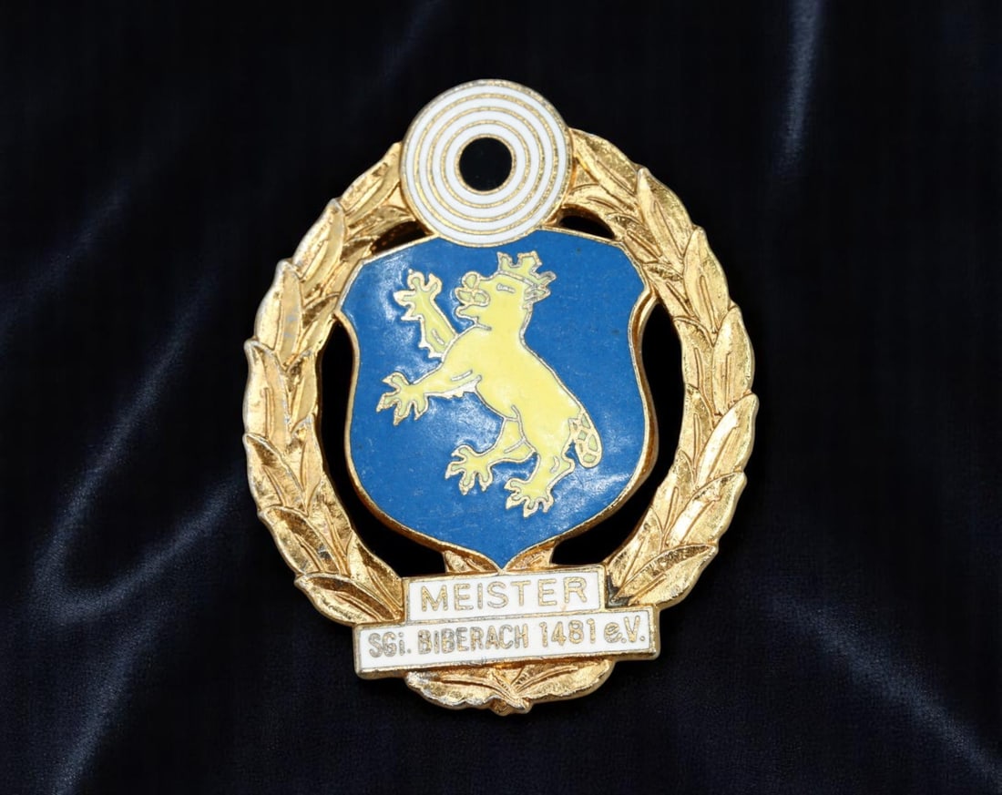 GERMANY: Biberach Champion's Laurel - SSG Meister Shooting Badge, ca. late 20th c., 45mm: This ornate shooting badge celebrates marksmanship excellence within the SSG Biberach 1481 e.V., one of Germany's long-established civilian shooting societies. Centered in a gold laurel wreath, a blue